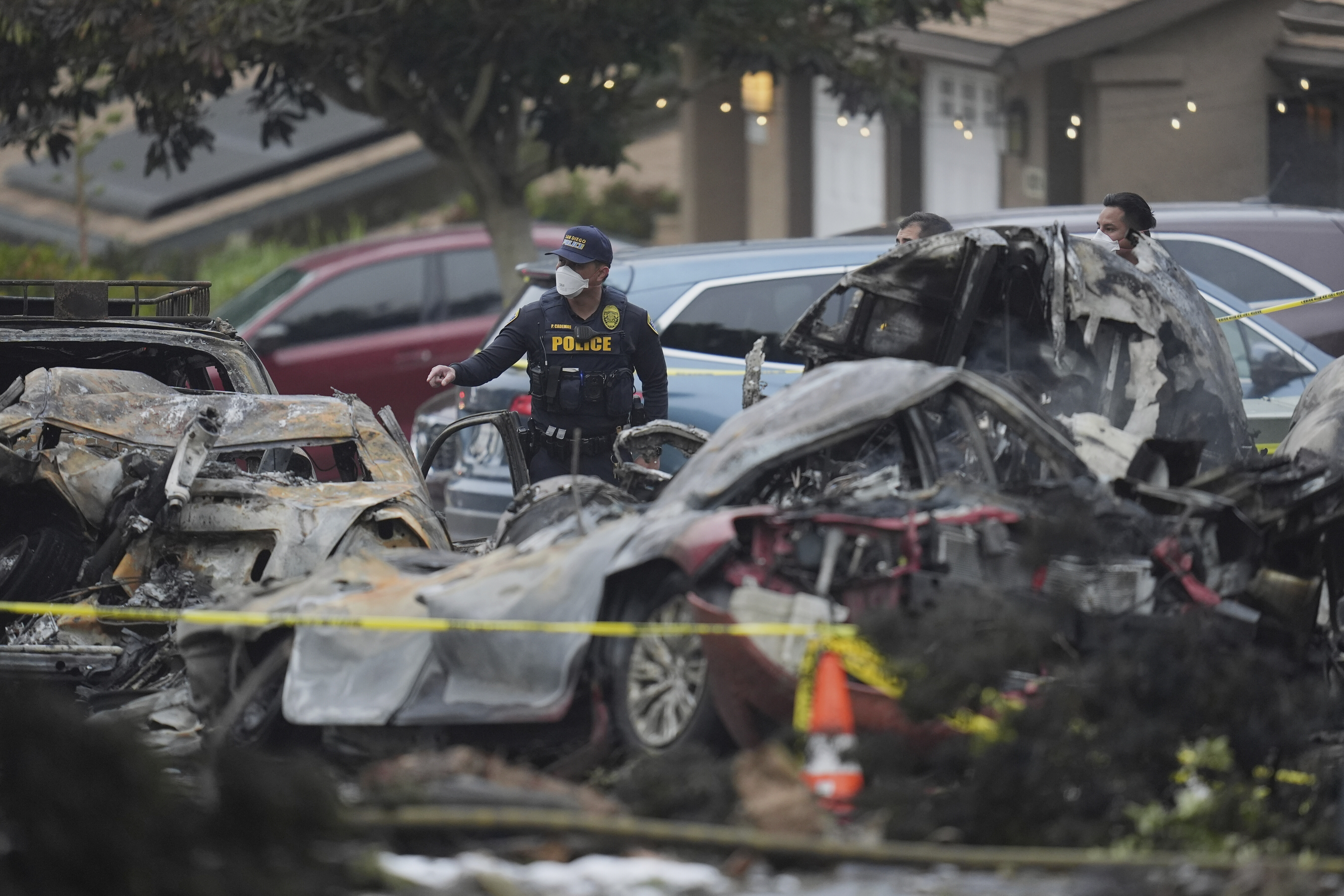 Authorities work the scene where a small plane crashed into a San Diego neighborhood, setting several homes on fire and forcing evacuations along several blocks early Thursday, May 22, 2025. (AP Photo/Gregory Bull)