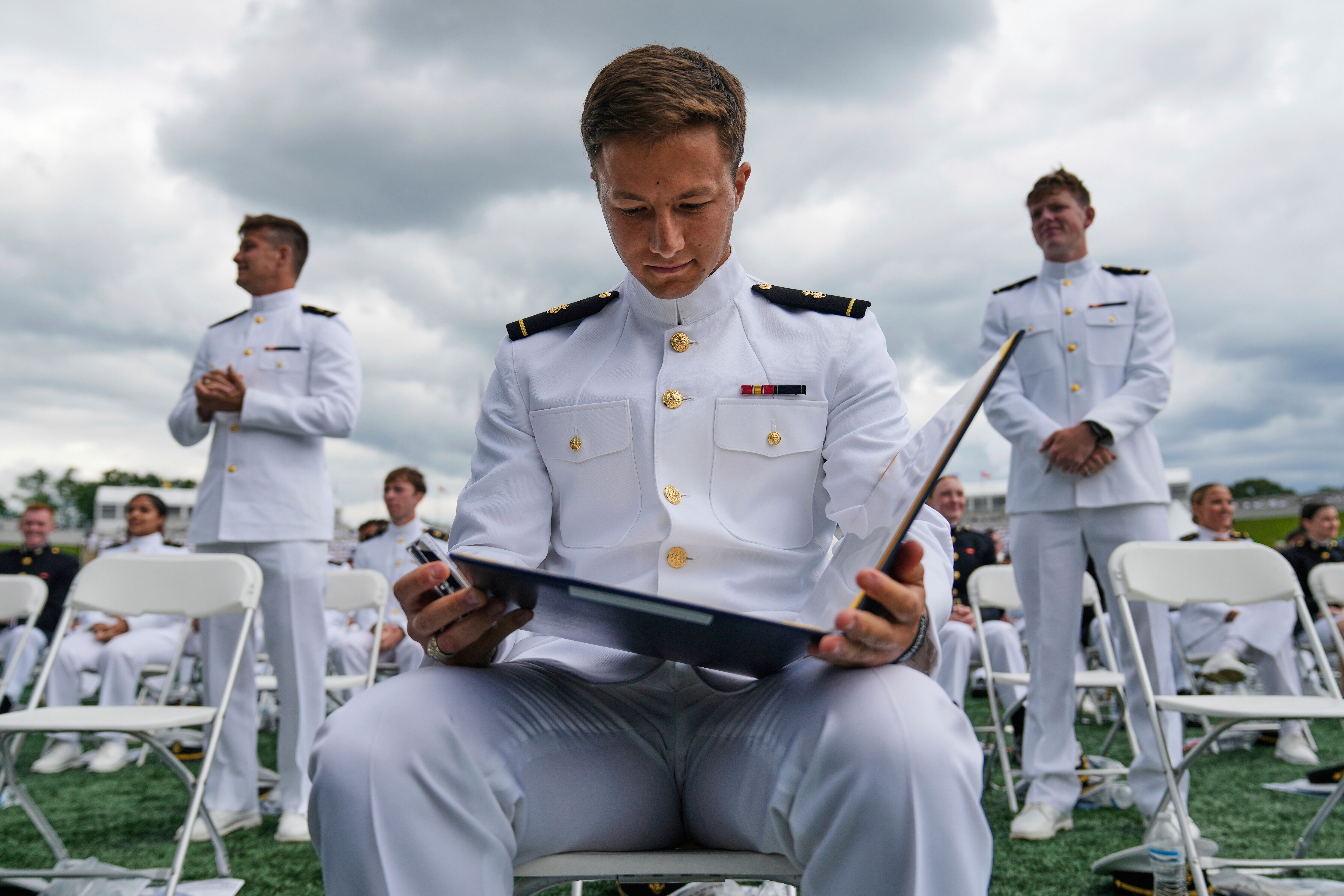 A graduate of the U.S. Naval Academy looks at his diploma after waking the stage during the academy's graduation and commissioning ceremony, at the U.S. Naval Academy in Annapolis, Md., Friday, May 23, 2025. (AP Photo/Stephanie Scarbrough)