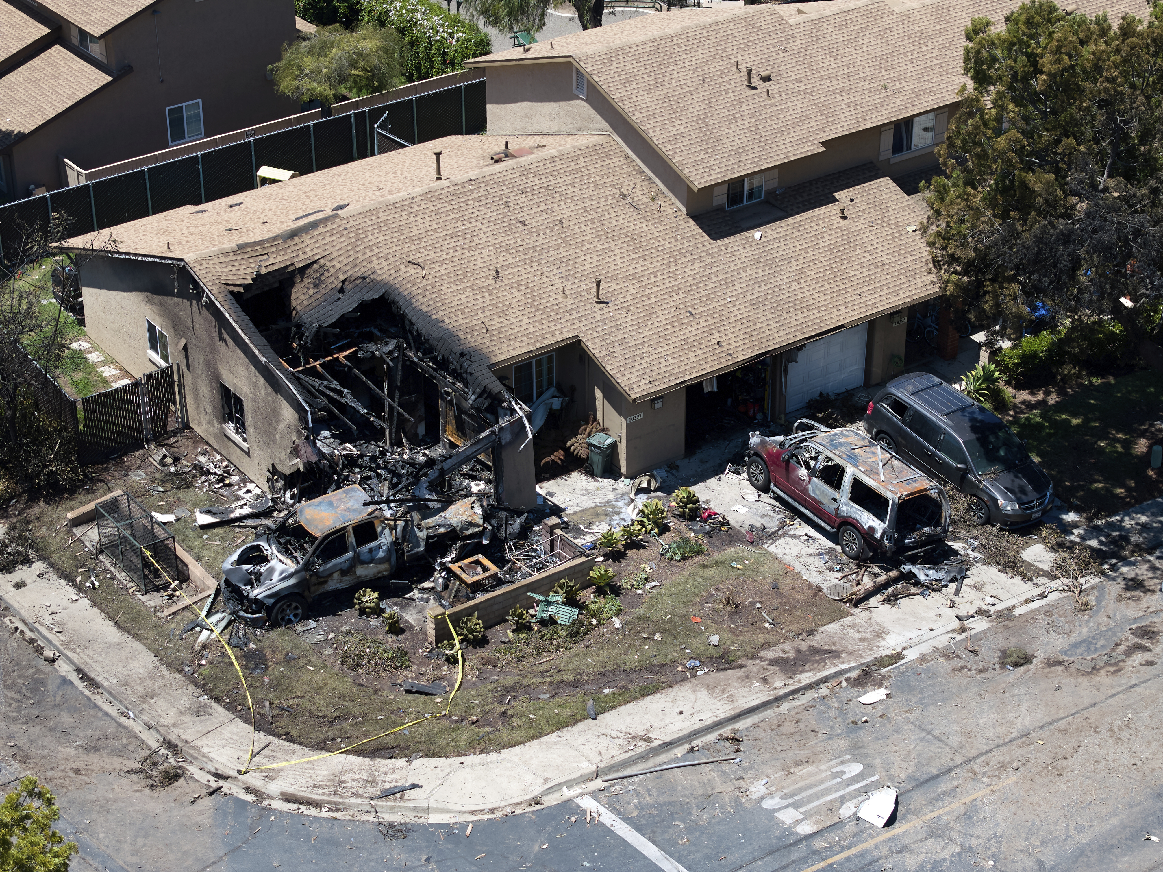 Debris covers the ground after a small plane crashed into a San Diego neighborhood, setting homes and cars on fire and forcing evacuations early Thursday, May 22, 2025. (AP Photo/William Liang)