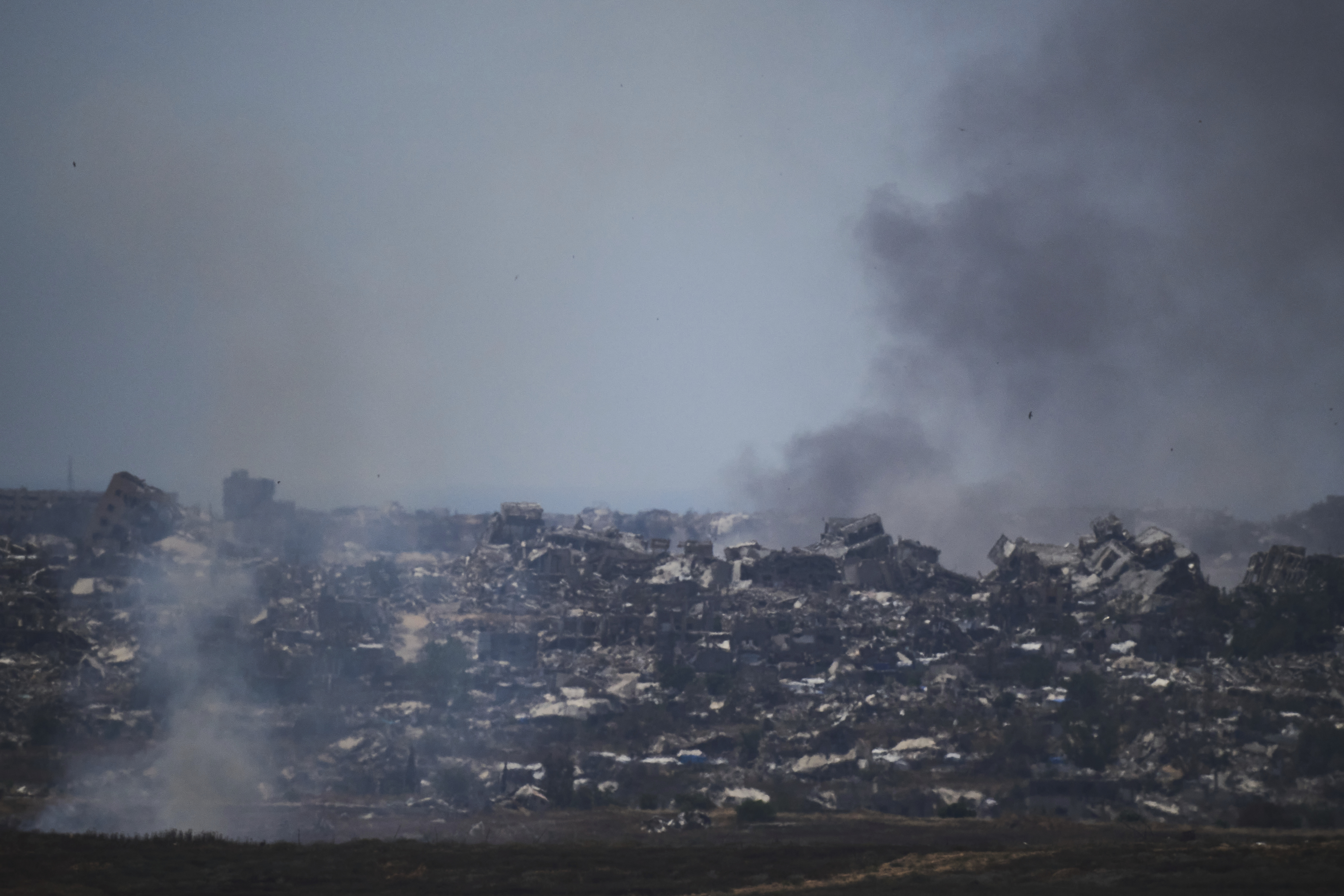 Smoke rises amid buildings that were destroyed during the Israeli ground and air operations in northern of Gaza Strip as seen from southern Israel, Friday, May 23, 2025. (AP Photo/Leo Correa)