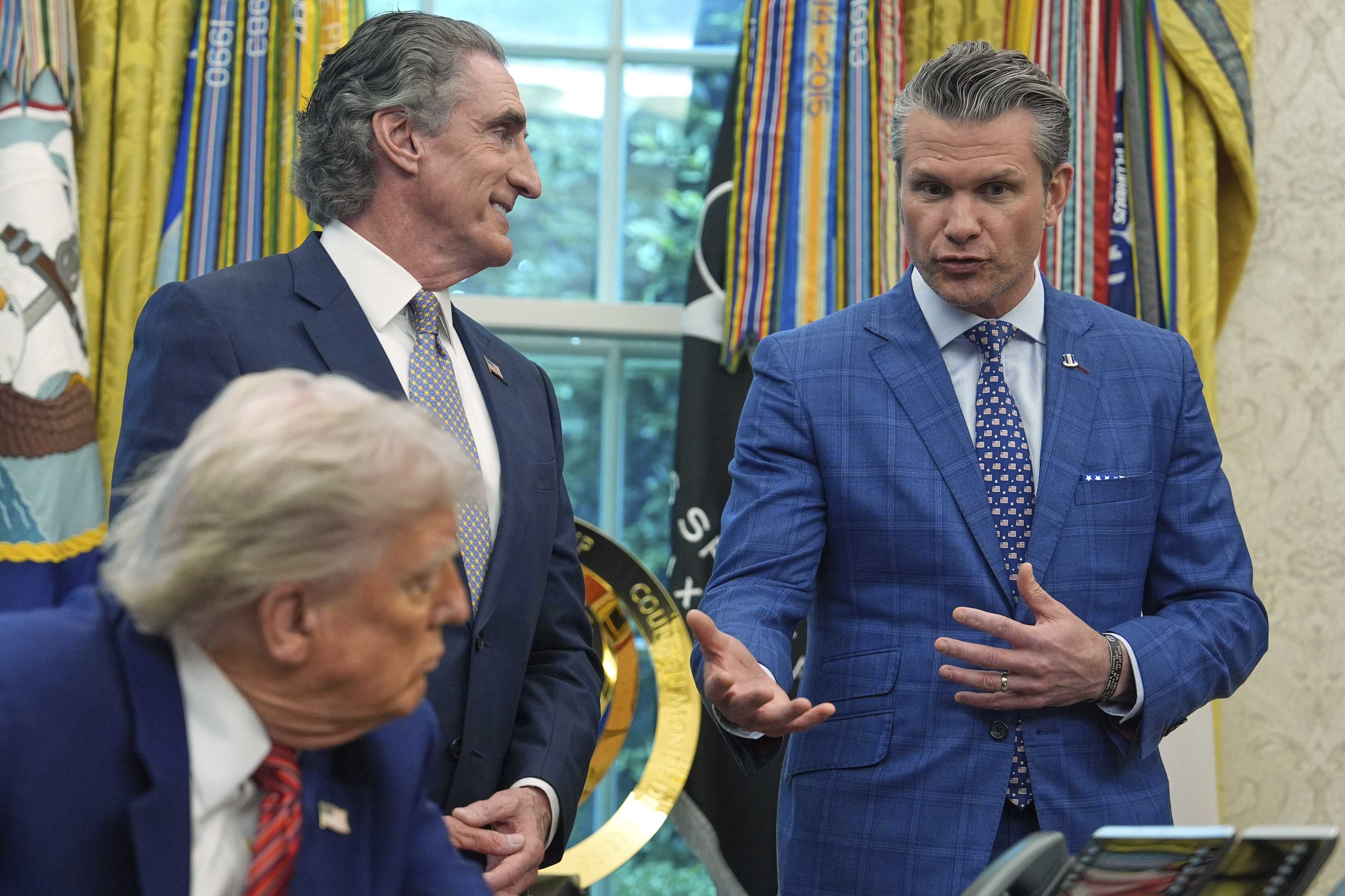 President Donald Trump and Interior Secretary Doug Burgum listen as Defense Secretary Pete Hegseth speaks before Trump signed executive orders regarding nuclear energy in the Oval Office of the White House, Friday, May 23, 2025, in Washington. (AP Photo/Evan Vucci)