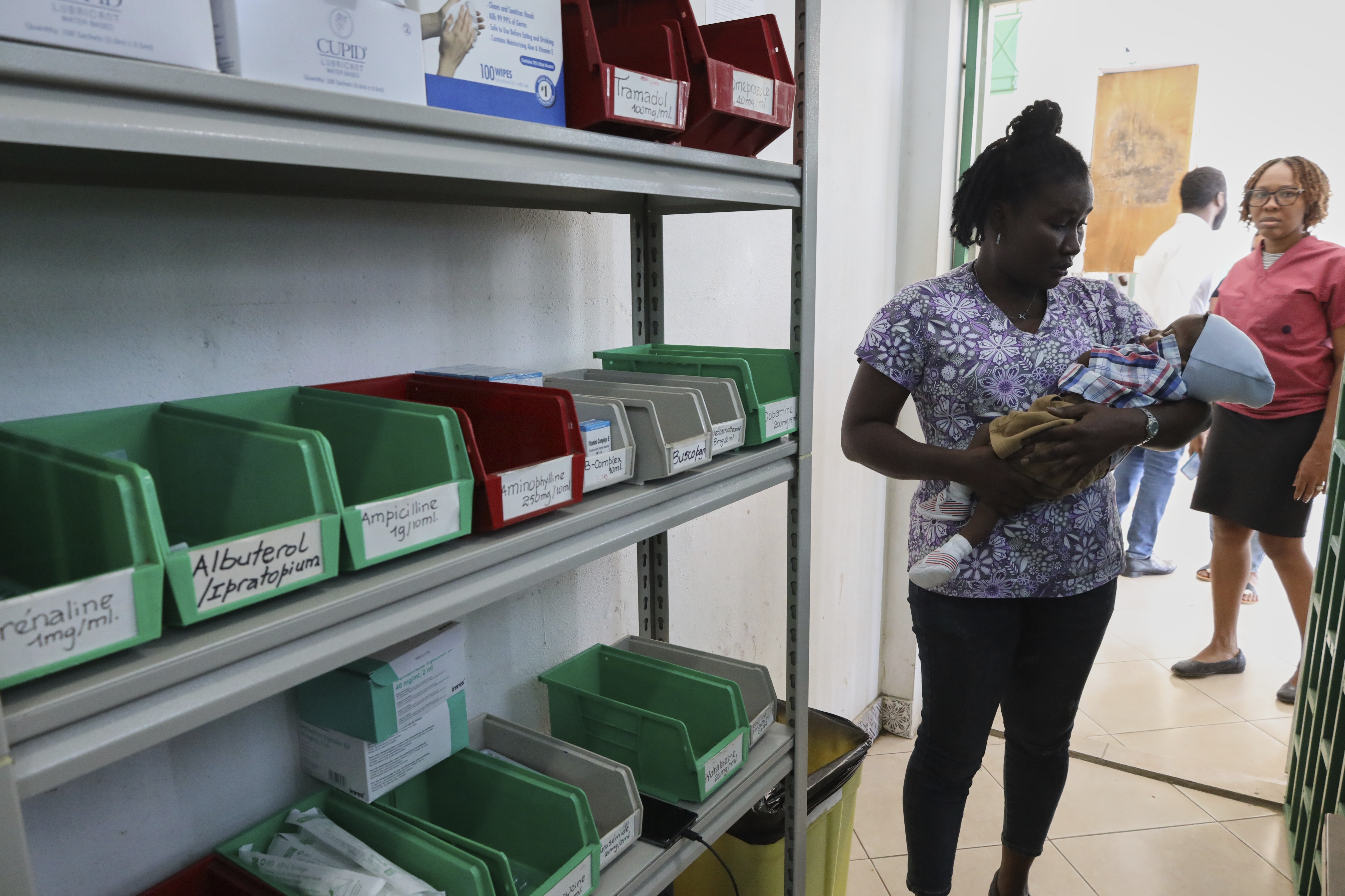 A patient cradles a baby while waiting to receive medicine at New Hope Hospital in Plaine-du-Nord, Haiti, Wednesday, May 21, 2025. (AP Photo/Patrice Noel)