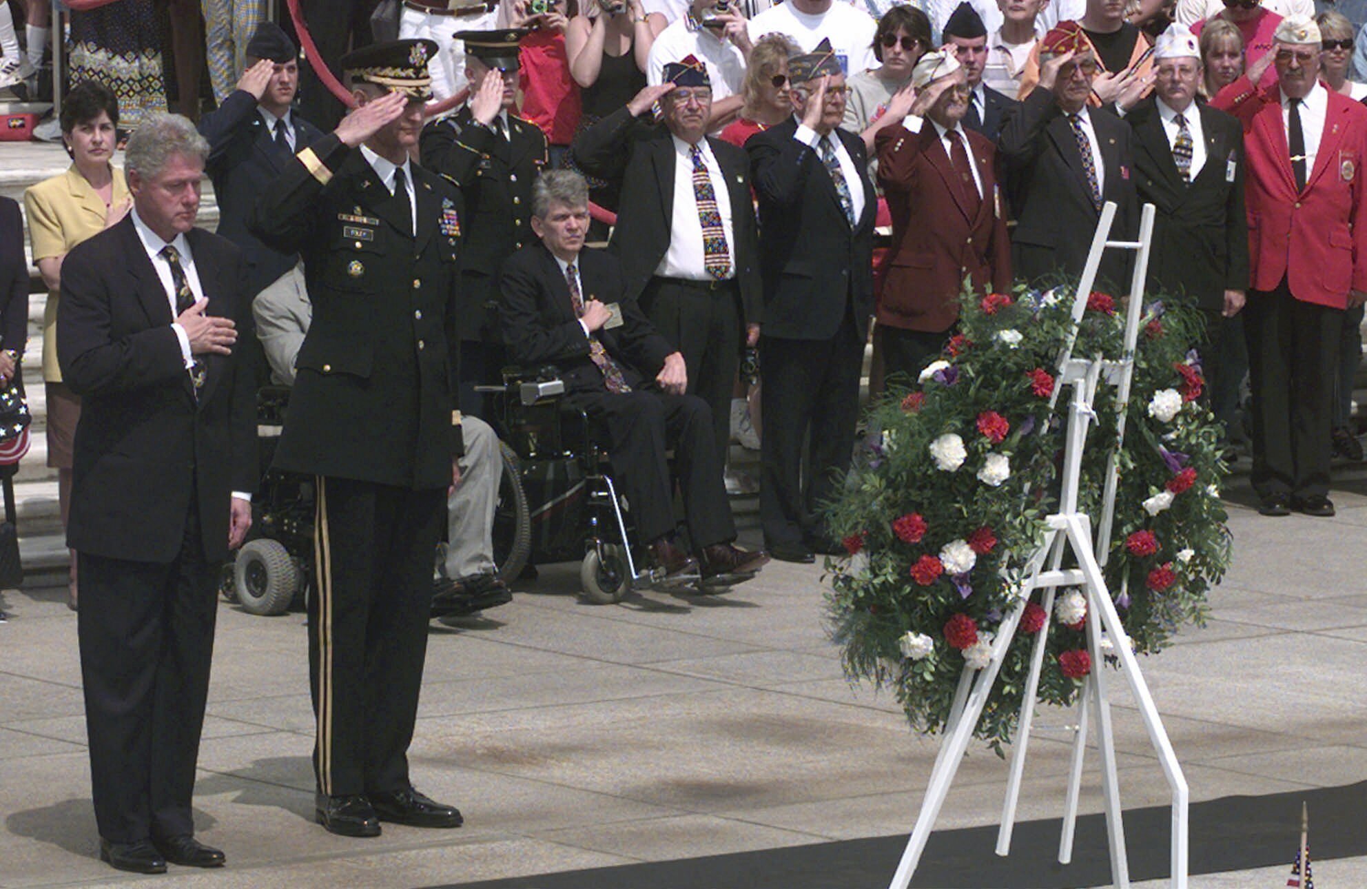 FILE - President Clinton stands with his hand over his heart during the playing of "Taps" at the Tomb of the Unknowns during Memorial Day ceremonies at Arlington National Cemetery Monday, May 25, 1998 in Arlington, Va. Standing next to the President is Major Gen. Robert Foley, the commanding general of the Military District of Washington. (AP Photo/Susan Walsh, File)
