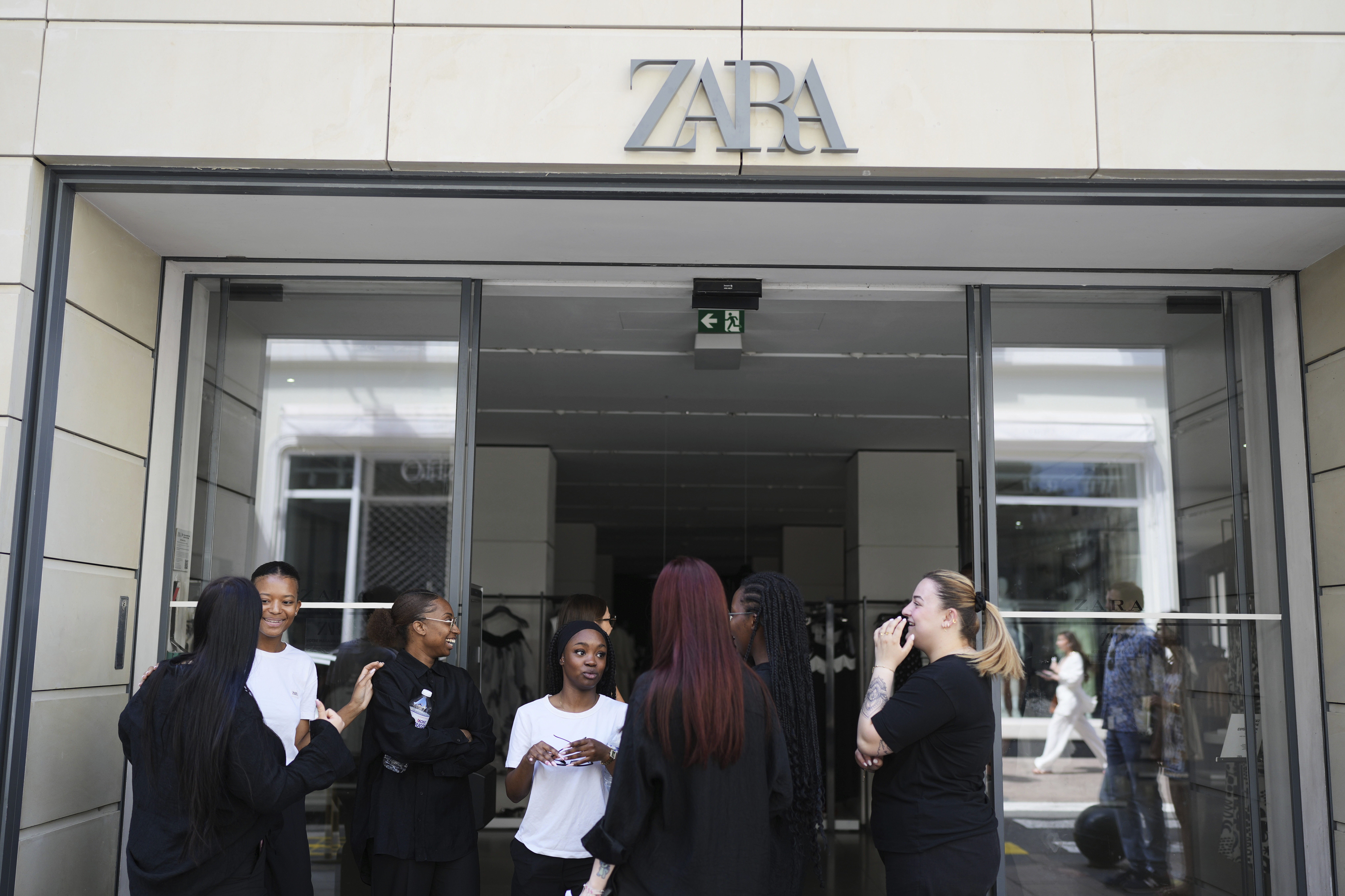 Employees stand outside a shop during an electricity outage in Cannes, southern France, Saturday, May 24, 2025. (AP Photo/Natacha Pisarenko)