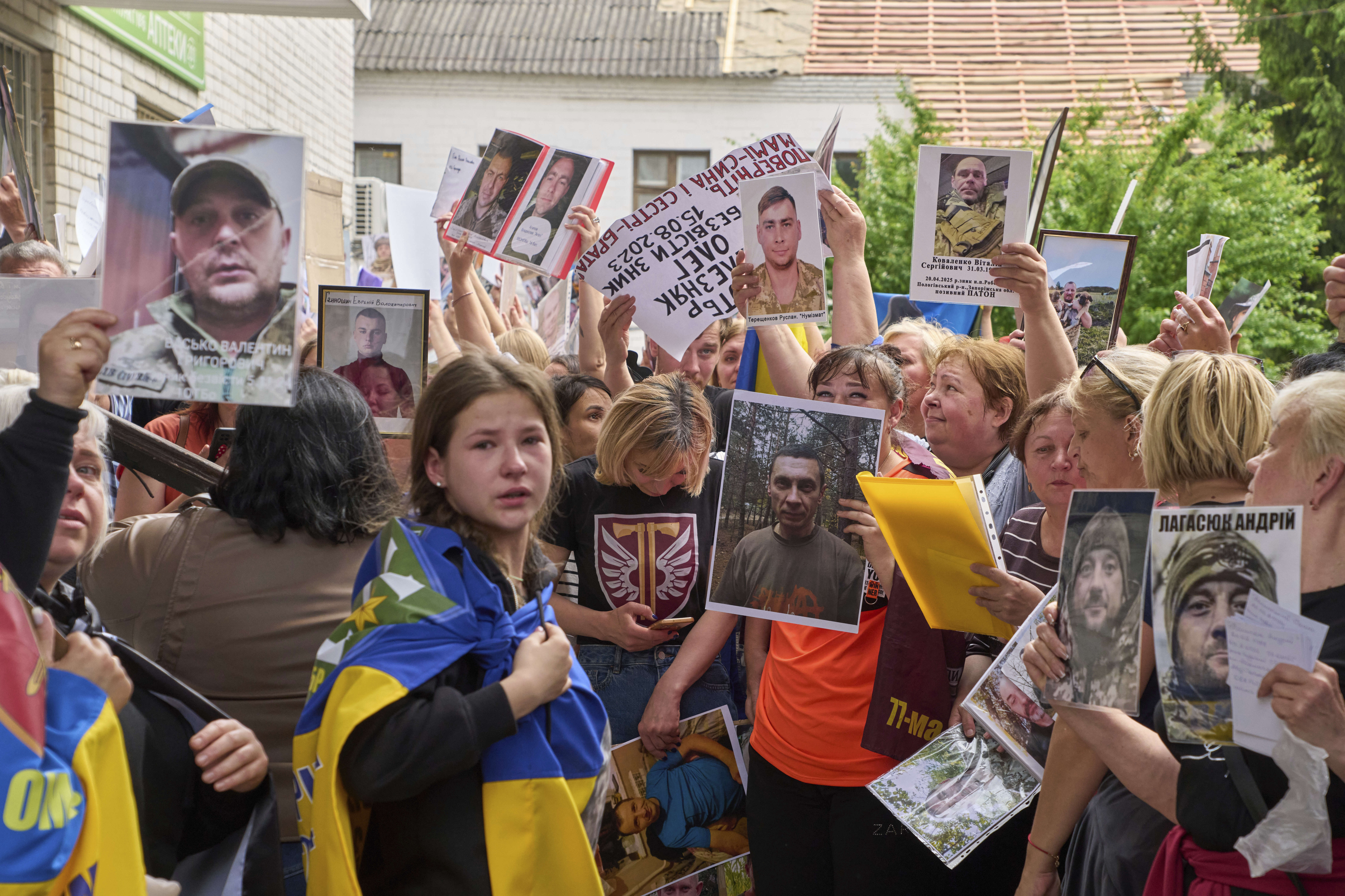 Relatives show photos of missing soldiers to POWs who came back from Russian captivity during an exchange of prisoners between Russia and Ukraine, in Chernyhiv region, Ukraine, Sunday, May 25, 2025. (AP Photo/Efrem Lukatsky)