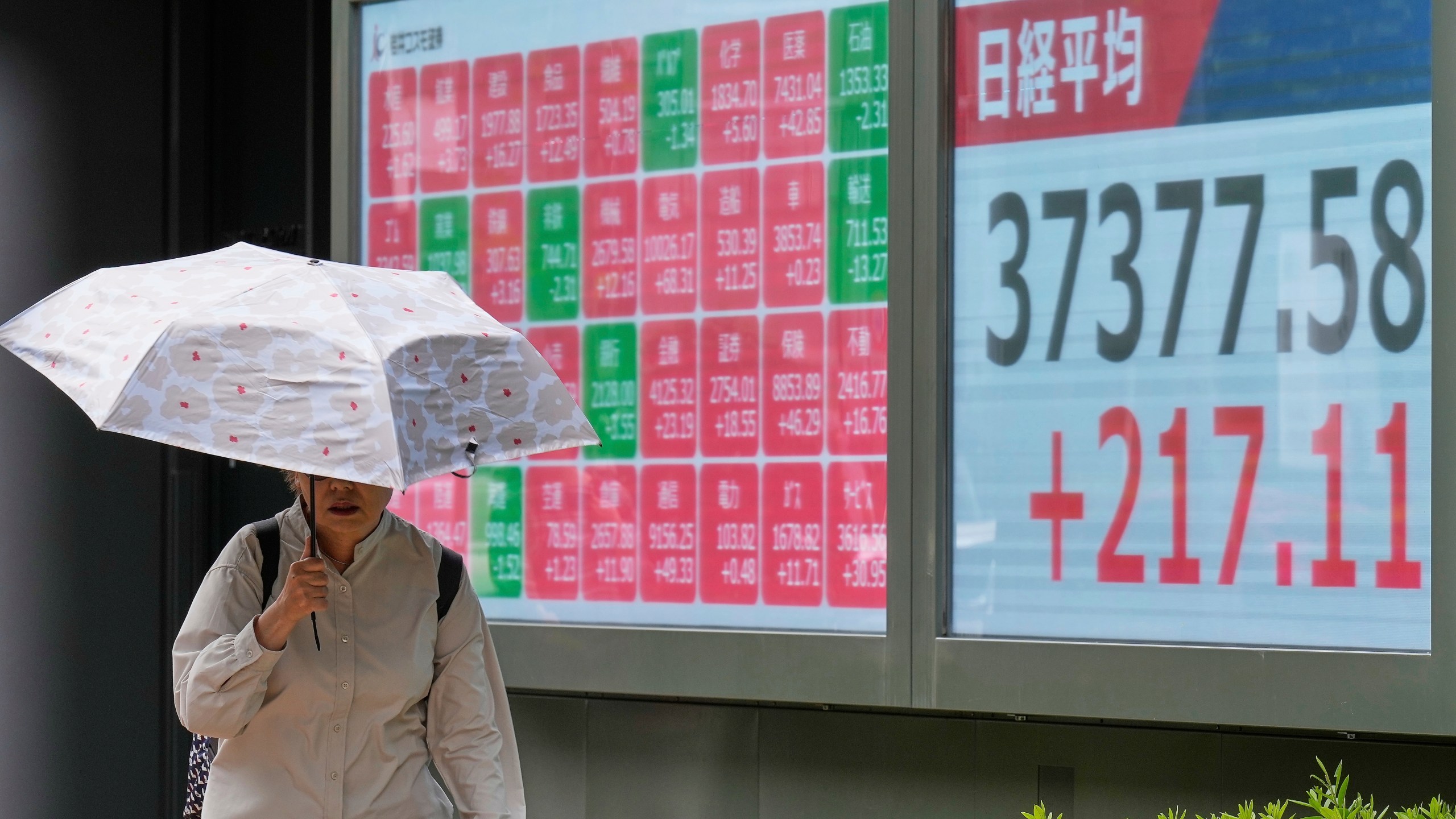 A person walks in front of an electronic stock board showing Japan's Nikkei index at a securities firm Monday, May 26, 2025, in Tokyo. (AP Photo/Eugene Hoshiko)
