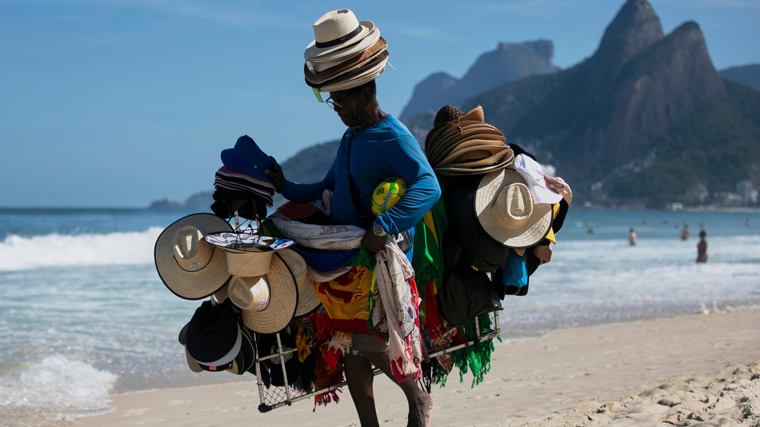 A vendor walks with his hats and beachwear along Ipanema Beach in Rio de Janeiro, Sunday, May 25, 2025. (AP Photo/Bruna Prado)
