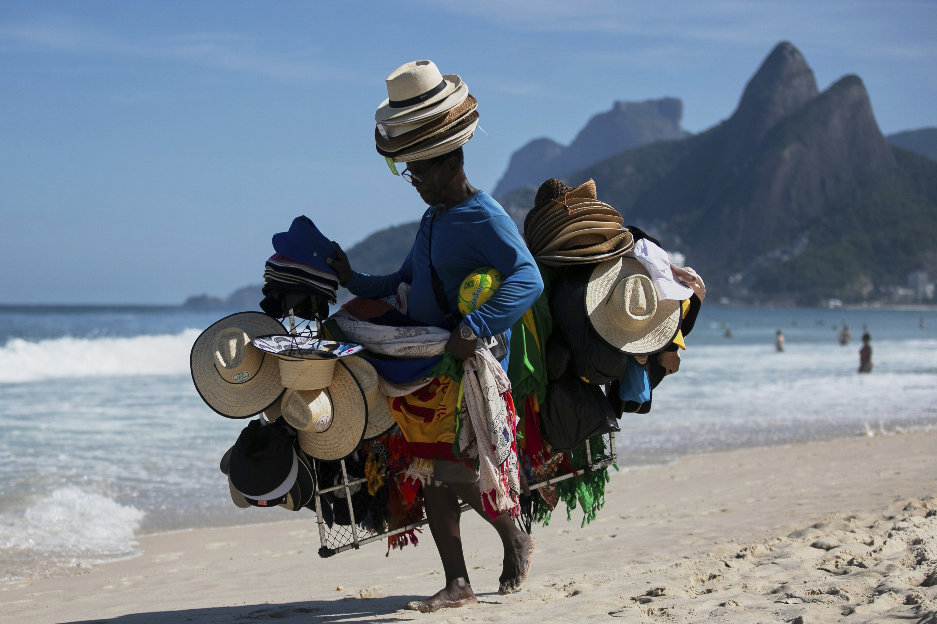 A vendor walks with his hats and beachwear along Ipanema Beach in Rio de Janeiro, Sunday, May 25, 2025. (AP Photo/Bruna Prado)
