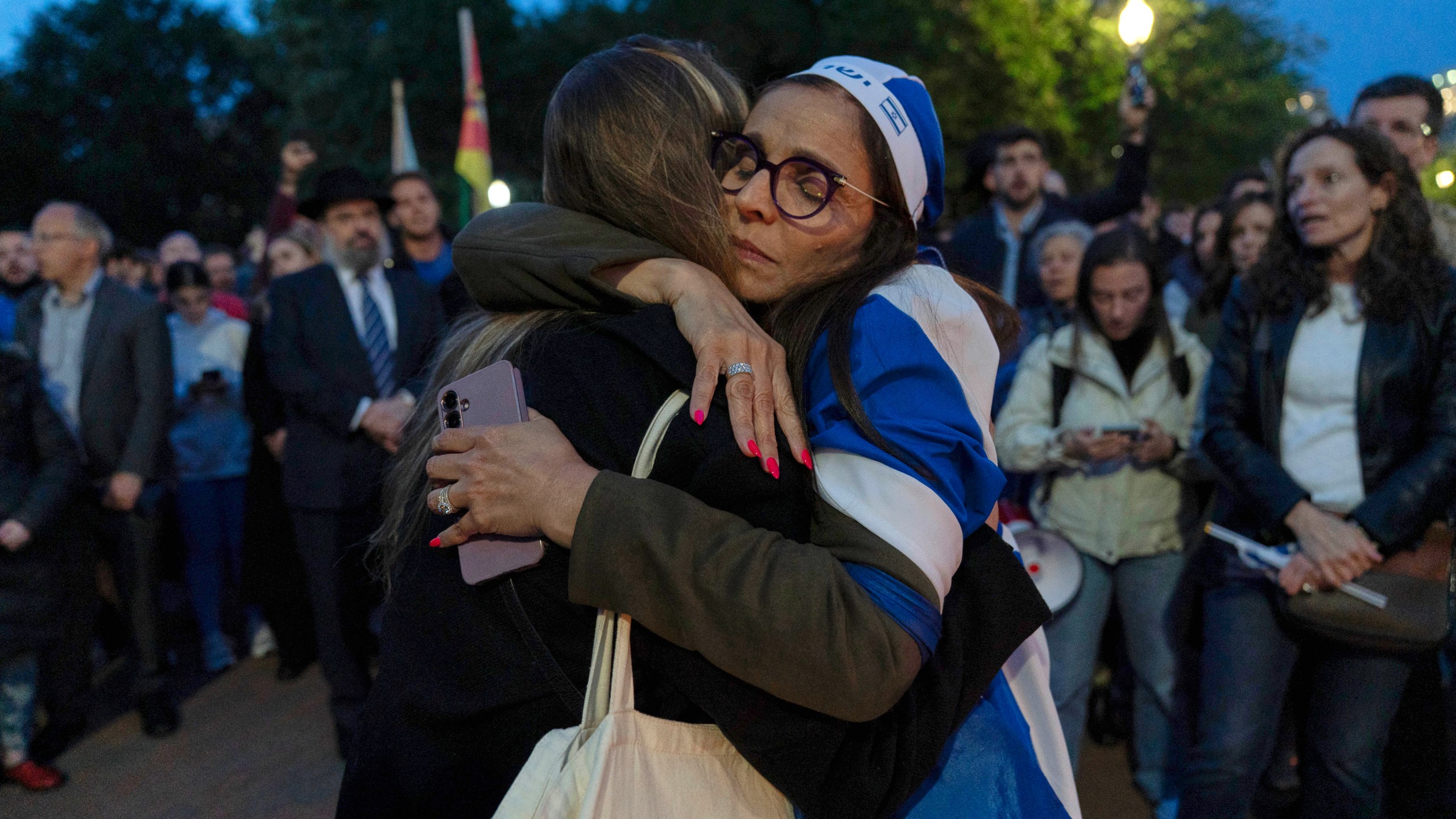 People embrace as they gather to light candles in a makeshift memorial to honor Yaron Lischinsky and Sarah Milgrim who were killed as they left an event at the Capital Jewish Museum in Washington, during a candlelight vigil outside of the White House in Washington, Thursday, May 22, 2025. (AP Photo/Jose Luis Magana)