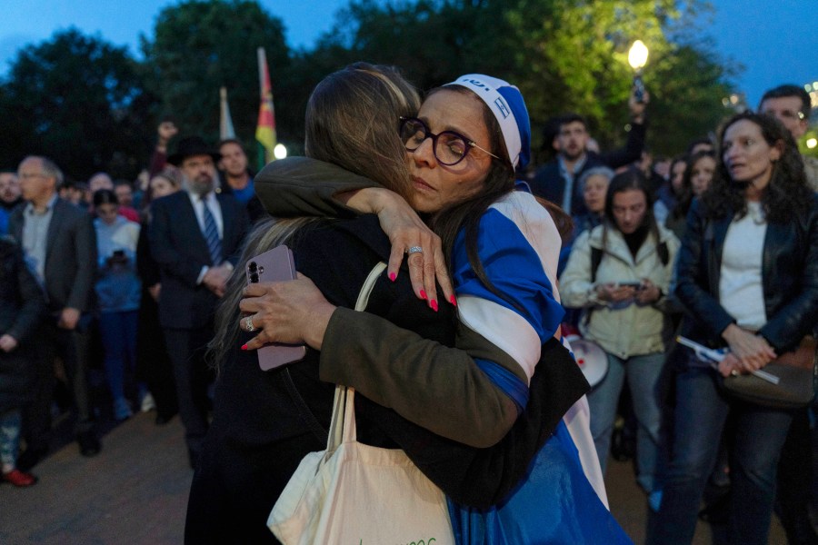 People embrace as they gather to light candles in a makeshift memorial to honor Yaron Lischinsky and Sarah Milgrim who were killed as they left an event at the Capital Jewish Museum in Washington, during a candlelight vigil outside of the White House in Washington, Thursday, May 22, 2025. (AP Photo/Jose Luis Magana)