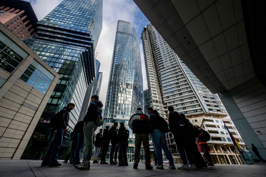 FILE - People stand in front of the city's largest construction site with four new high-rise buildings in Frankfurt, Germany, Sept. 24, 2024. (AP Photo/Michael Probst, file)