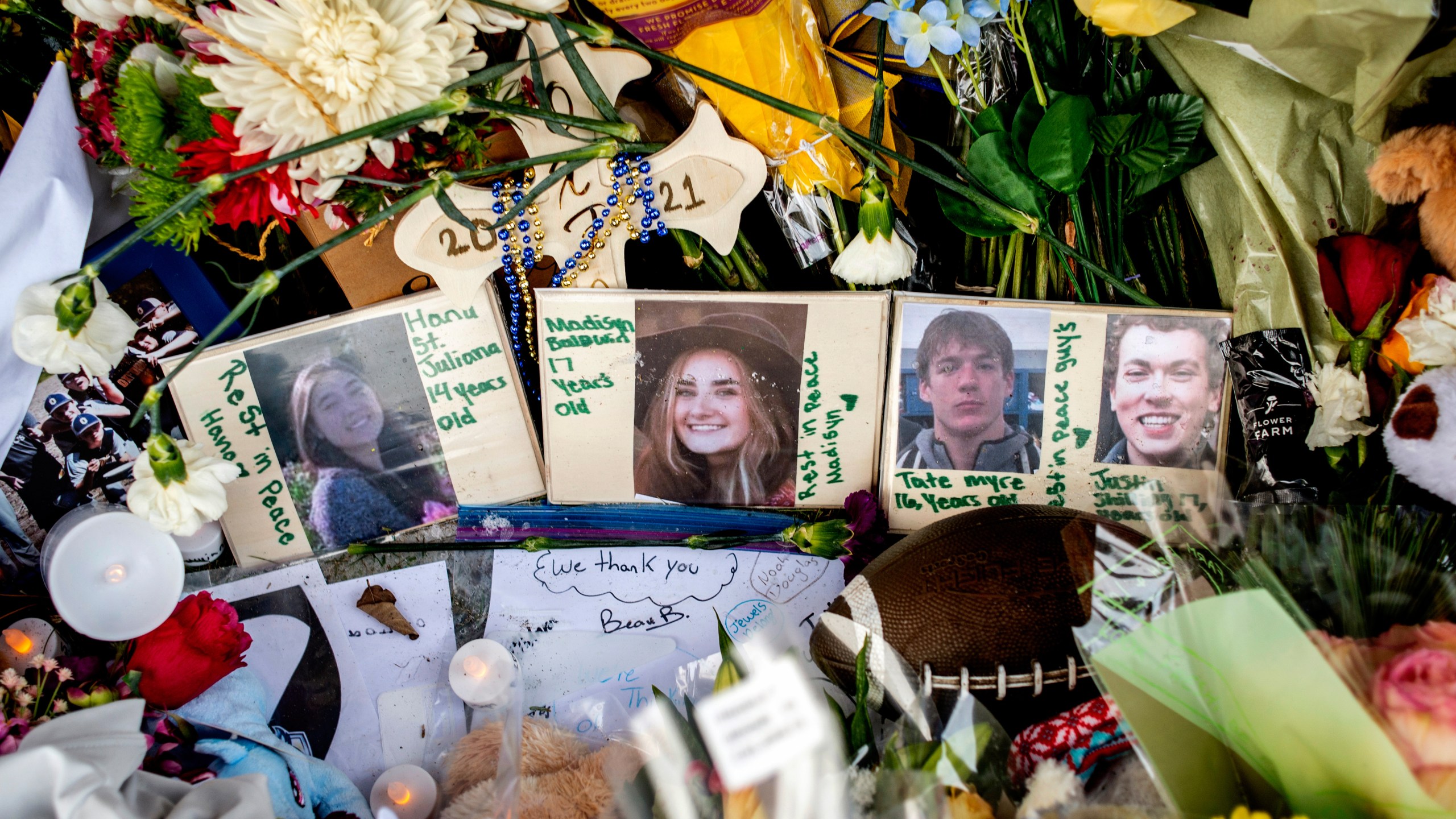 FILE - Photographs of four students — Hana St. Juliana, 14; Madisyn Baldwin, 17; Tate Myre, 16; and Justin Shilling, 17 — sit among bouquets of flowers, teddy bears and other personal items left at the memorial site for victims of the school shooting, outside Oxford High School, Dec. 7, 2021, in Oxford, Mich. (Jake May/The Flint Journal via AP, File)