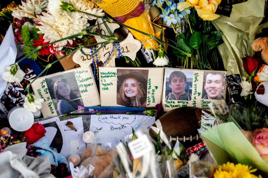 FILE - Photographs of four students — Hana St. Juliana, 14; Madisyn Baldwin, 17; Tate Myre, 16; and Justin Shilling, 17 — sit among bouquets of flowers, teddy bears and other personal items left at the memorial site for victims of the school shooting, outside Oxford High School, Dec. 7, 2021, in Oxford, Mich. (Jake May/The Flint Journal via AP, File)