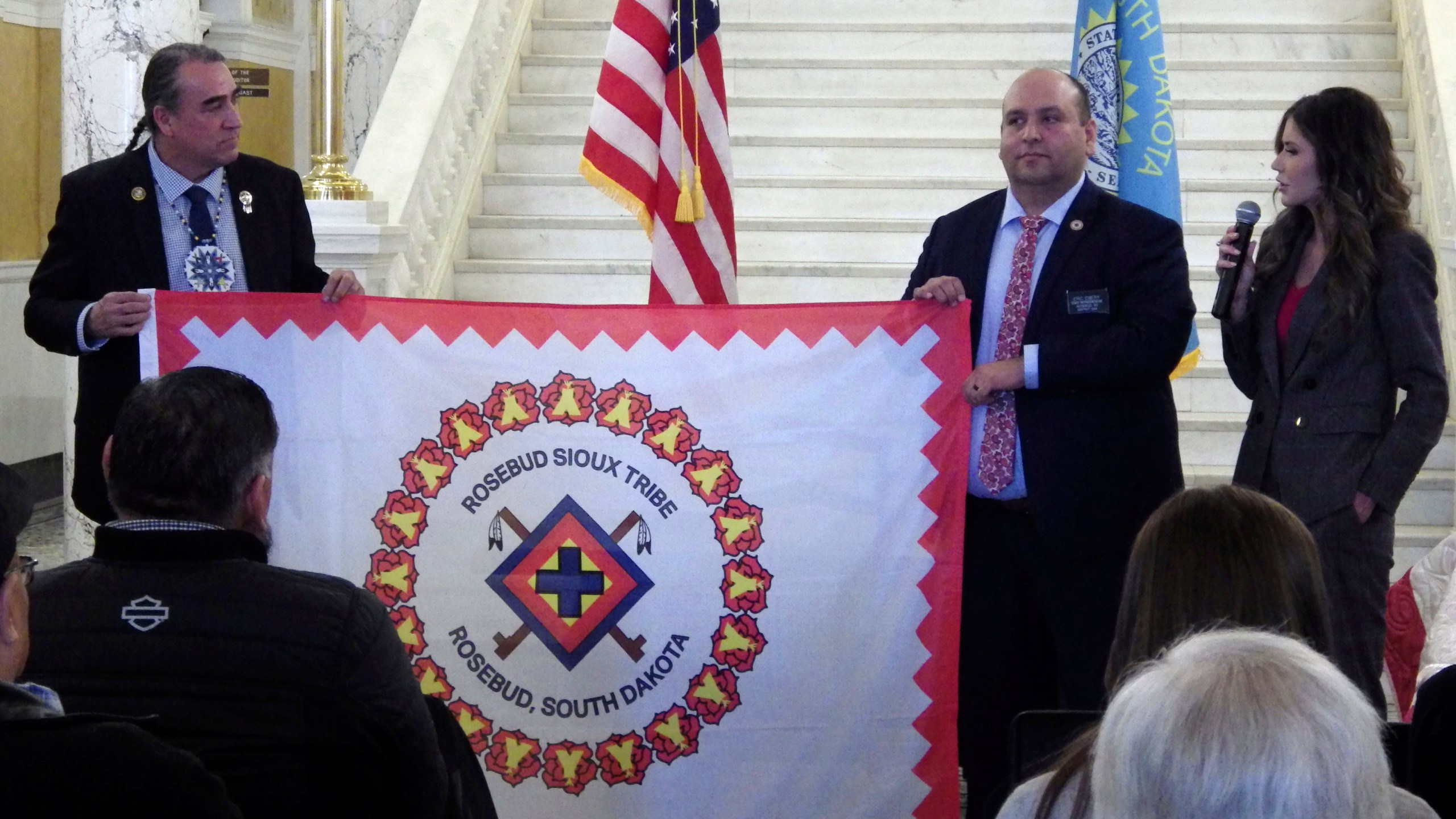 FILE - South Dakota state Democratic Sen. Shawn Bordeaux, left, and Rep. Eric Emery hold the flag of the Rosebud Sioux Tribe on Jan. 10, 2024, at the state Capitol in Pierre, S.D. At right is South Dakota Republican Gov. Kristi Noem. (AP Photo/Jack Dura, file)