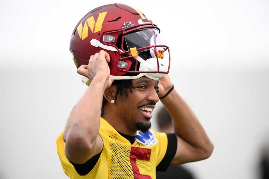 Washington Commanders quarterback Jayden Daniels puts on his helmet during NFL football practice, Wednesday, May 28, 2025, in Ashburn, Va. (AP Photo/Nick Wass)