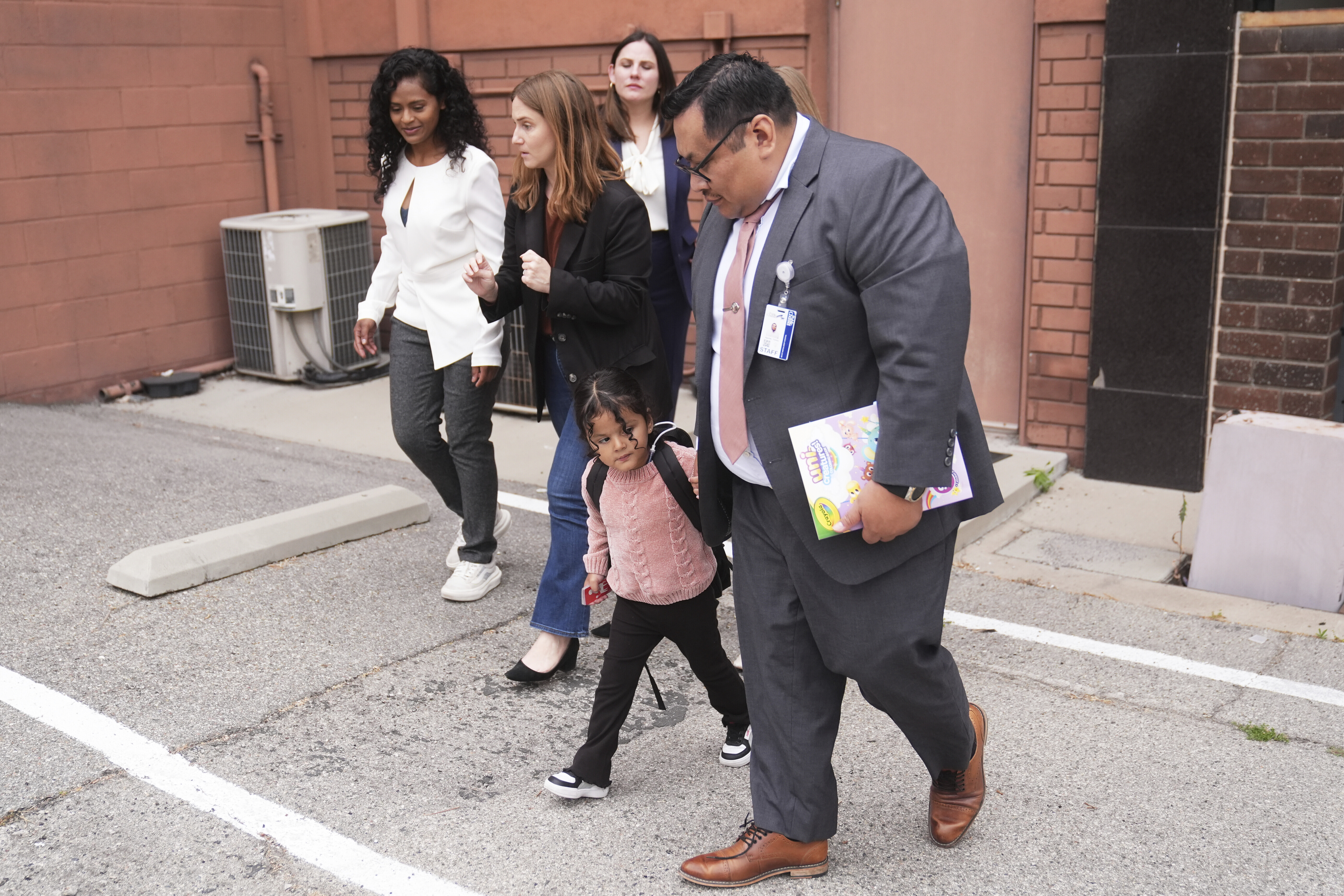 A 4-year-old Mexican girl, who has short bowel syndrome, holds the hand of Yonny Aguilar, a senior paralegal at Public Counsel, as she and her mother, far left, leave a news conference in Los Angeles, Wednesday, May 28, 2025, after their humanitarian parole was terminated and they were ordered to self-deport. (AP Photo/Jae C. Hong)
