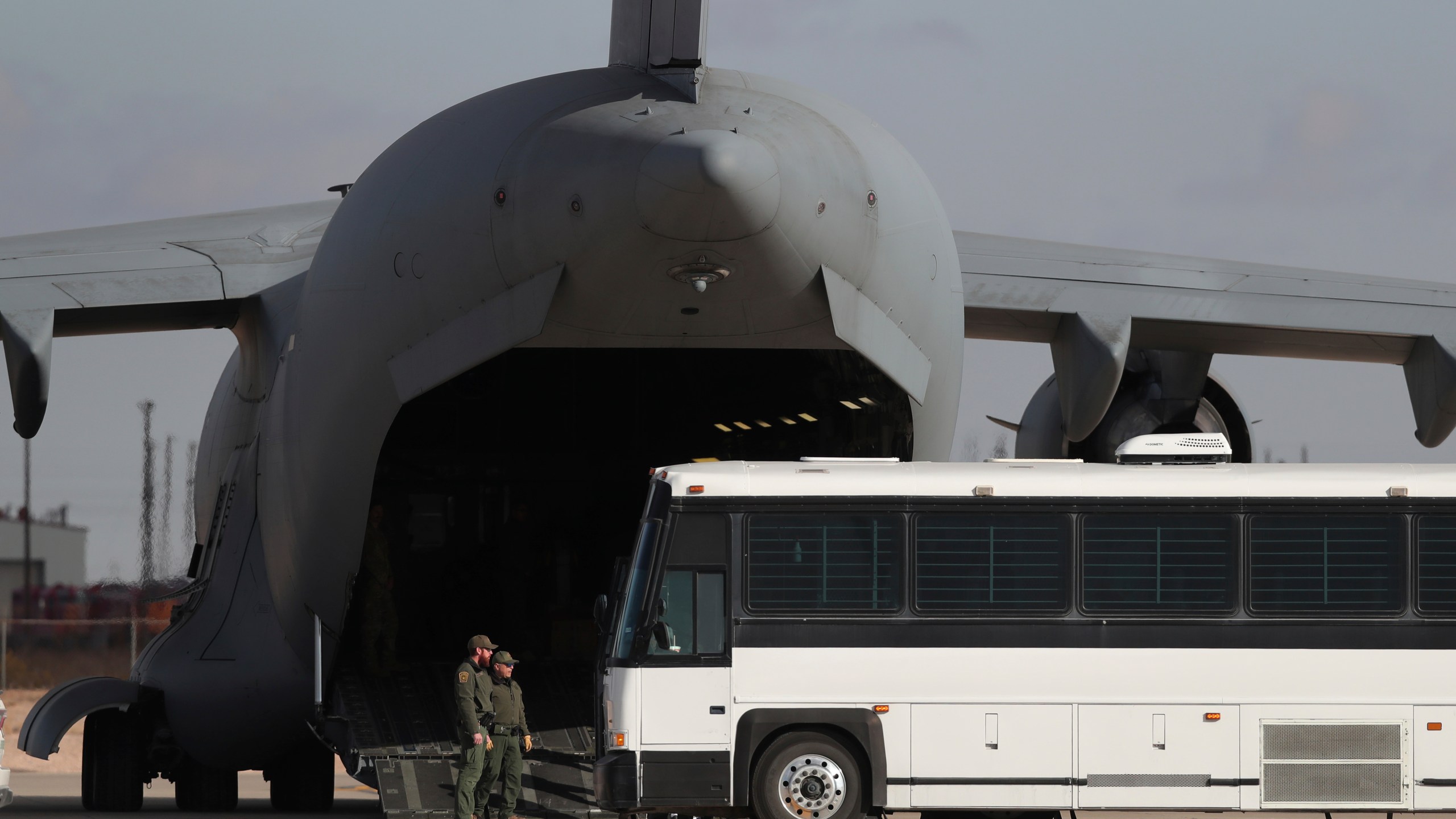 FILE - A military aircraft waits for migrants to board from a bus at Fort Bliss in El Paso, Tx., Thursday, Jan. 30, 2025, before deporting them to Guatemala. (AP Photo/Christian Chavez, File)