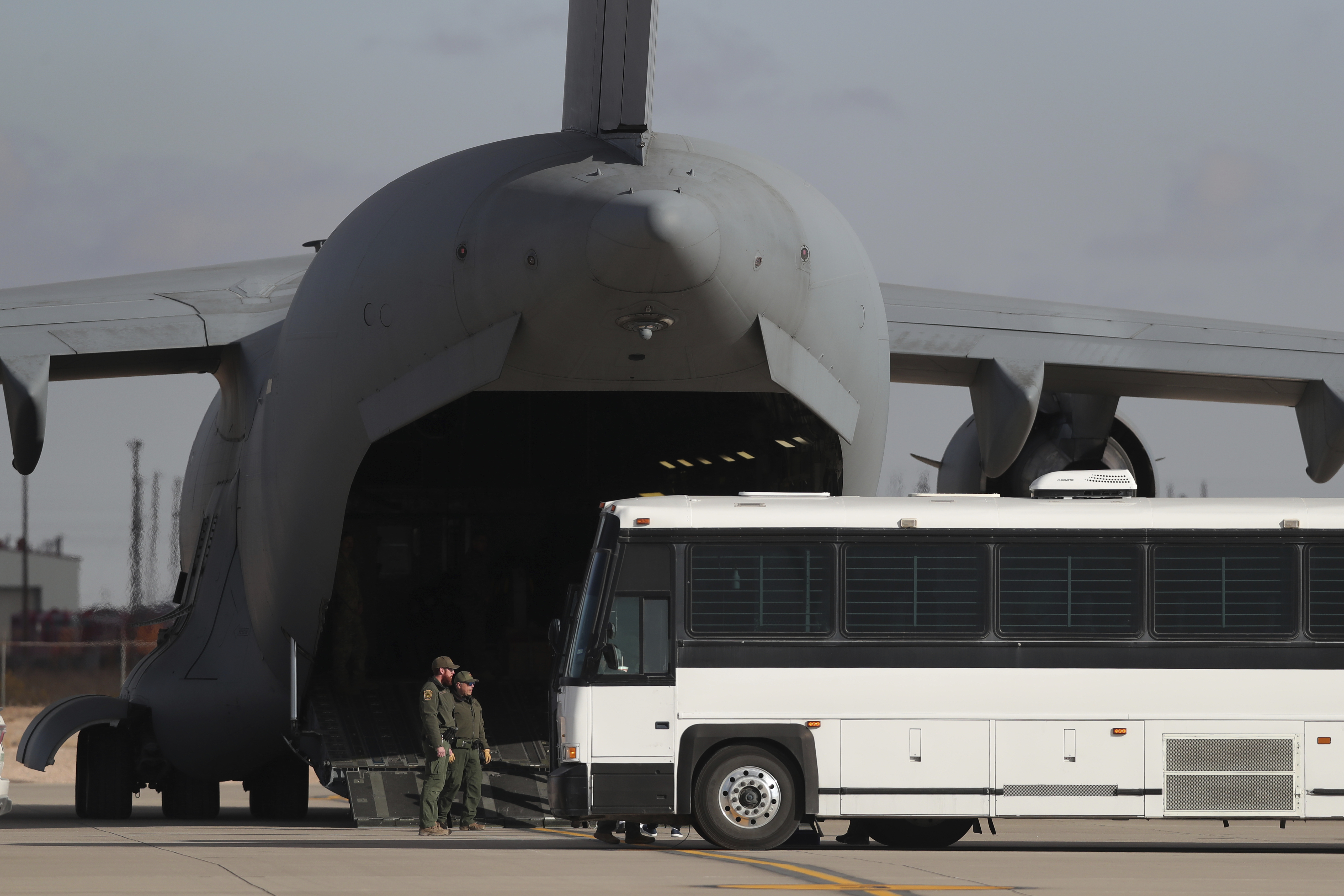 FILE - A military aircraft waits for migrants to board from a bus at Fort Bliss in El Paso, Tx., Thursday, Jan. 30, 2025, before deporting them to Guatemala. (AP Photo/Christian Chavez, File)