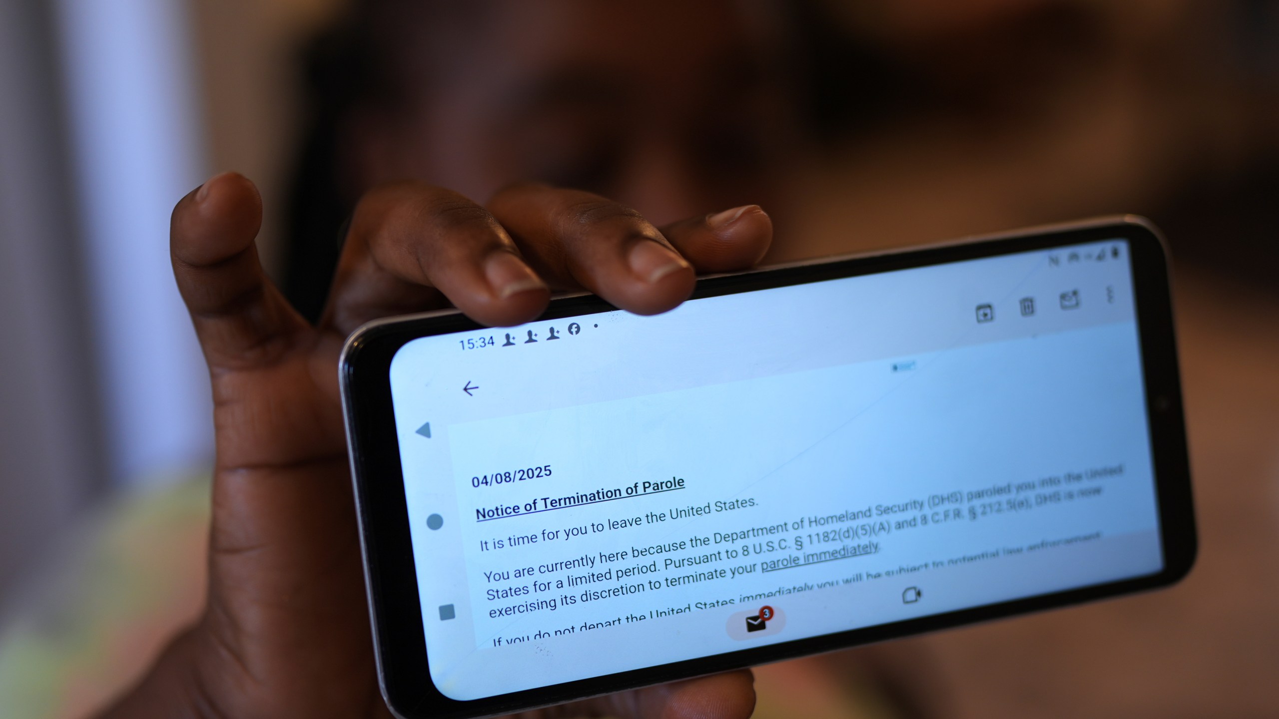 Nicole, a Haitian immigrant who works for a meat processing plant, shows an email terminating her parole, Sunday, April 13, 2025, in Dumas, Texas. (AP Photo/Eric Gay)