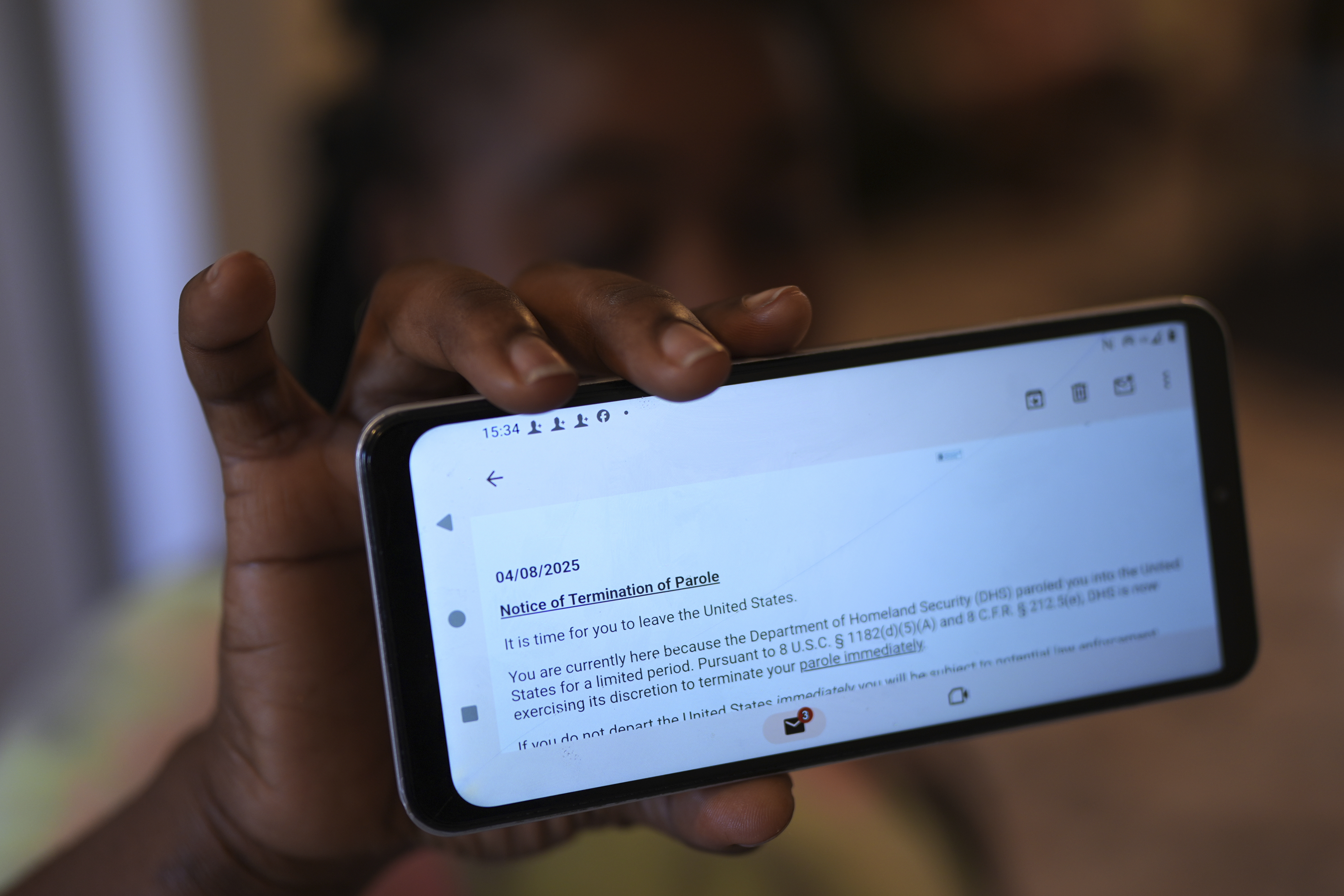 Nicole, a Haitian immigrant who works for a meat processing plant, shows an email terminating her parole, Sunday, April 13, 2025, in Dumas, Texas. (AP Photo/Eric Gay)