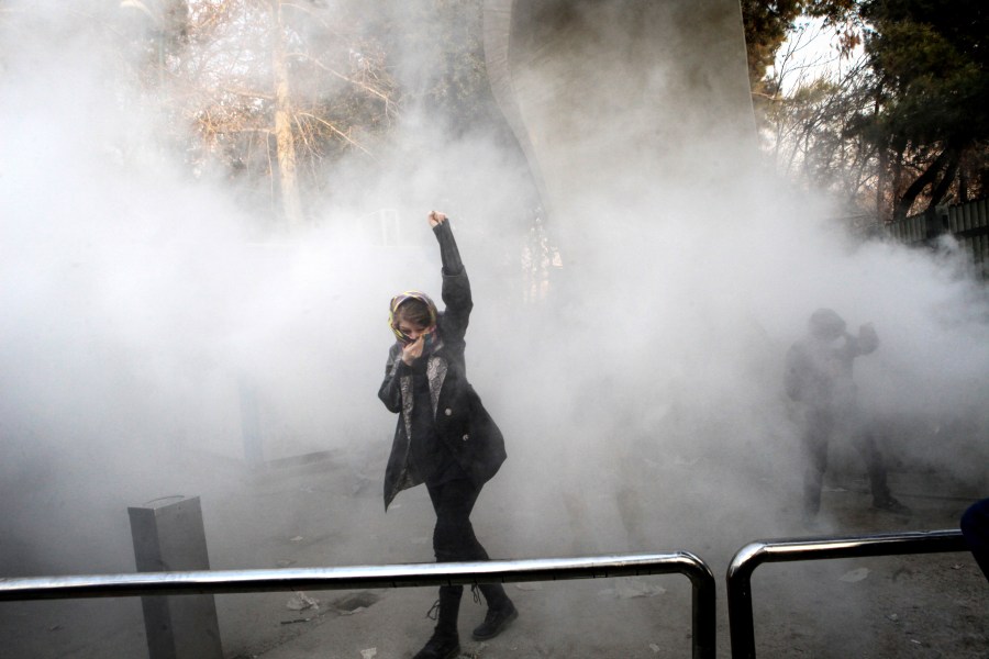 FILE - In this photo taken by a person not employed by the Associated Press and obtained by the AP outside Iran, a university student attends a protest inside Tehran University after a smoke grenade was thrown by anti-riot Iranian police, in Tehran, Iran, Dec. 30, 2017. (AP Photo, File)