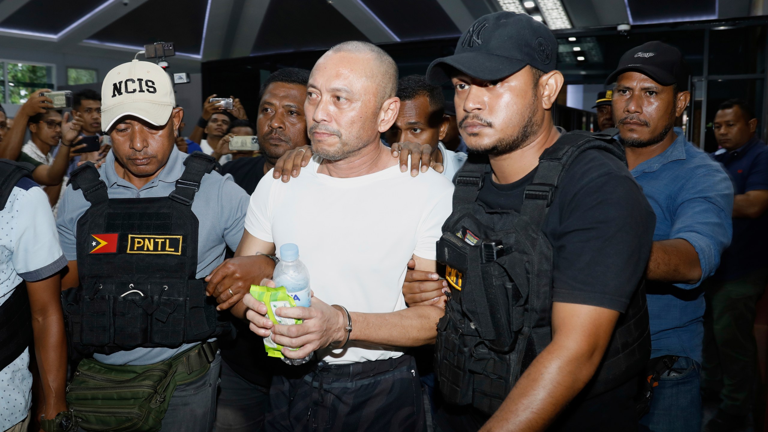 A former Filipino Congressman charged with multiple murders in the Philippines, Arnolfo Teves Jr, center, is escorted by police officers in Dili, East Timor, Thursday, May 29, 2025. (AP Photo/Sony da Costa)