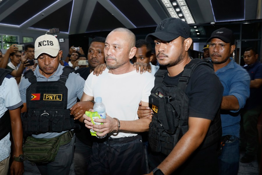 A former Filipino Congressman charged with multiple murders in the Philippines, Arnolfo Teves Jr, center, is escorted by police officers in Dili, East Timor, Thursday, May 29, 2025. (AP Photo/Sony da Costa)