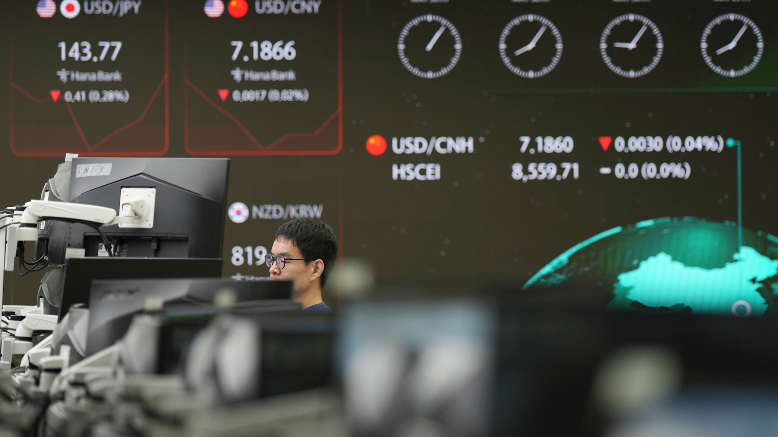 A dealer watches computer monitors near the screens showing the foreign exchange rates at a dealing room of Hana Bank in Seoul, South Korea, Friday, May 30, 2025. (AP Photo/Lee Jin-man)