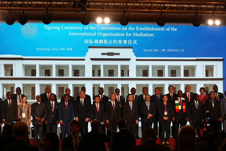 Chinese Foreign Minister Wang Yi, center, attends the signing ceremony of “the Convention on the Establishment of the International Organization for Mediation”, in Hong Kong, Friday, May 30, 2025. (AP Photo/Jonathan Lee)