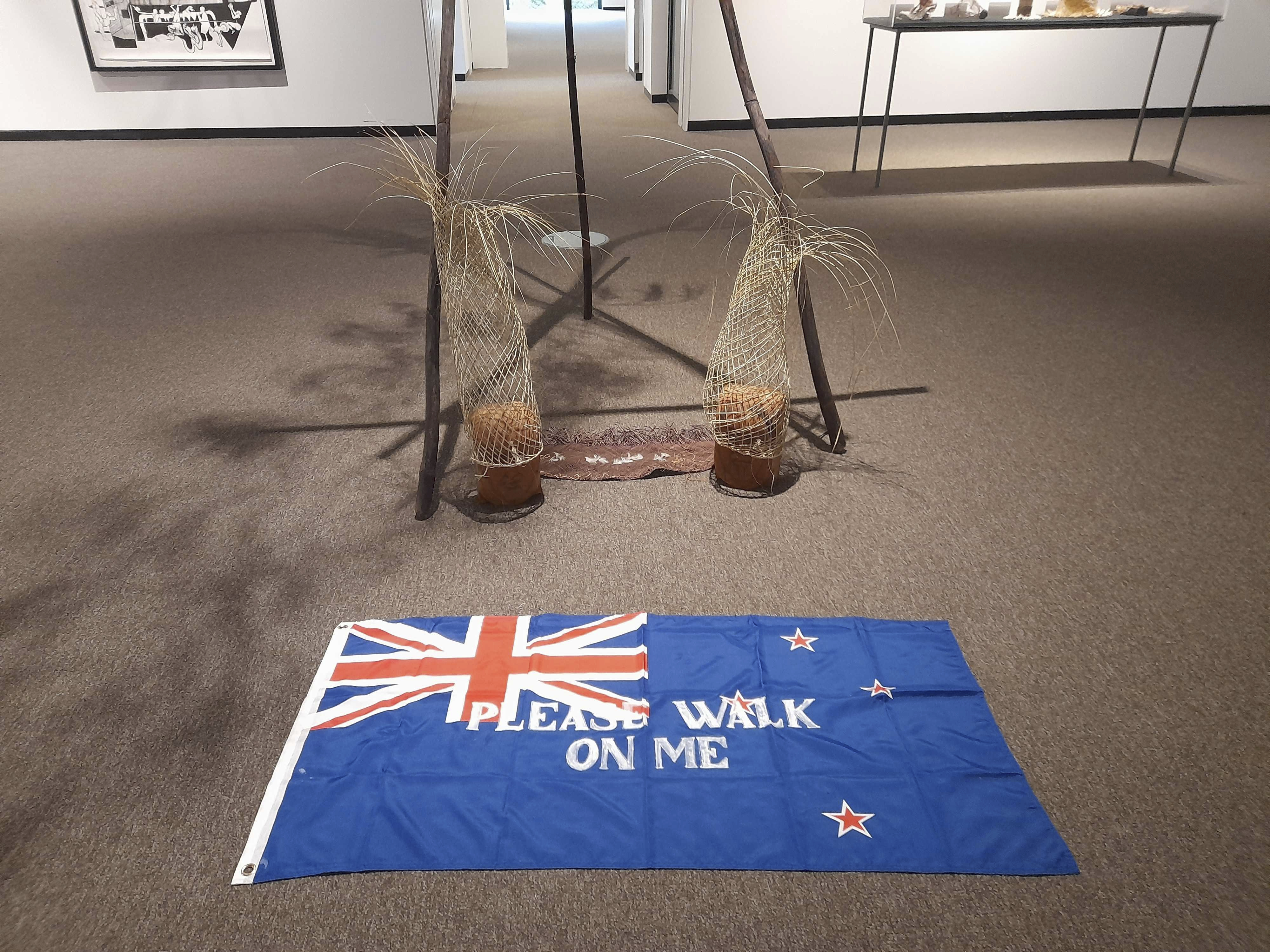 An artwork titled Flagging the Future, a cloth New Zealand flag with the words "please walk on me" stenciled across it by Māori artist Diane Prince, is displayed on the floor on Tuesday, May 27, 2025, at the Suter Art Gallery in Nelson, New Zealand. (Catherine Hubbard/Nelson Mail/STUFF via AP)