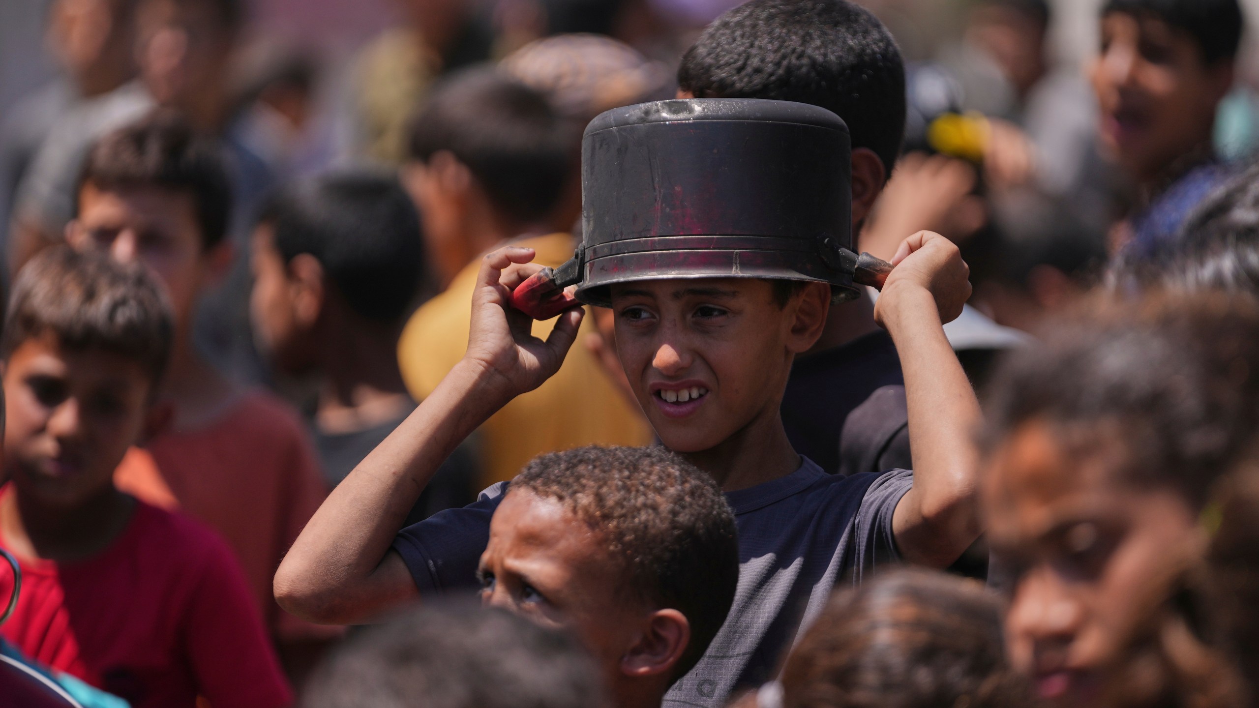 A young Palestinian waits to collect donated food at a food distribution kitchen in Deir al-Balah, Gaza Strip, Friday, May 30, 2025. (AP Photo/Abdel Kareem Hana)