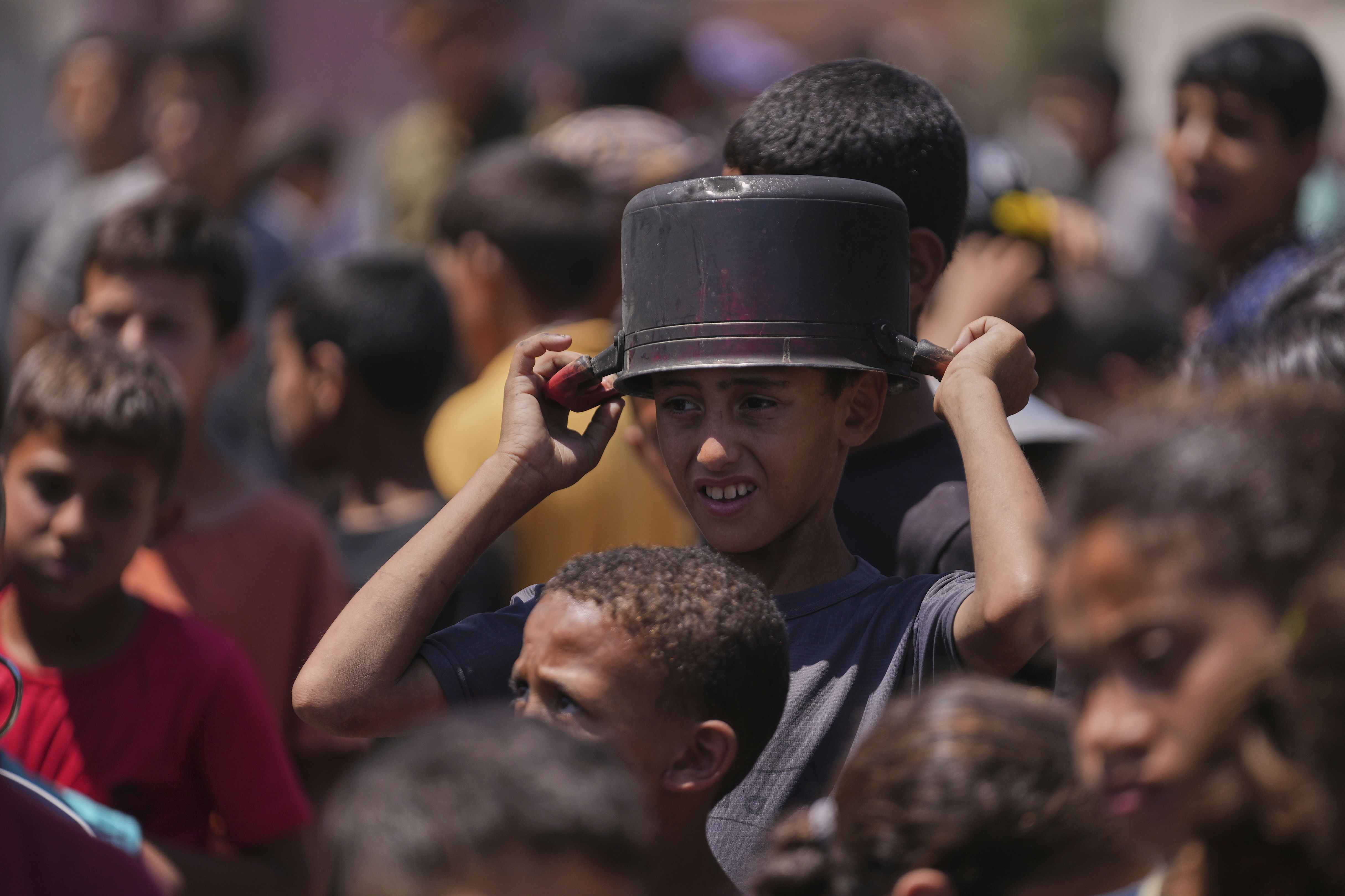 A young Palestinian waits to collect donated food at a food distribution kitchen in Deir al-Balah, Gaza Strip, Friday, May 30, 2025. (AP Photo/Abdel Kareem Hana)