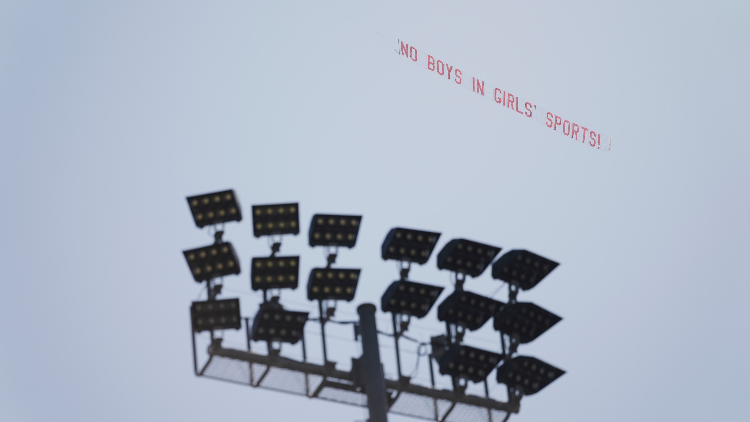 A banner reading "NO BOYS IN GIRLS' SPORTS!" is flown above Veteran's Memorial Stadium during the California high school track-and-field championships in Clovis, Calif., Friday, May 30, 2025. (AP Photo/Jae C. Hong)