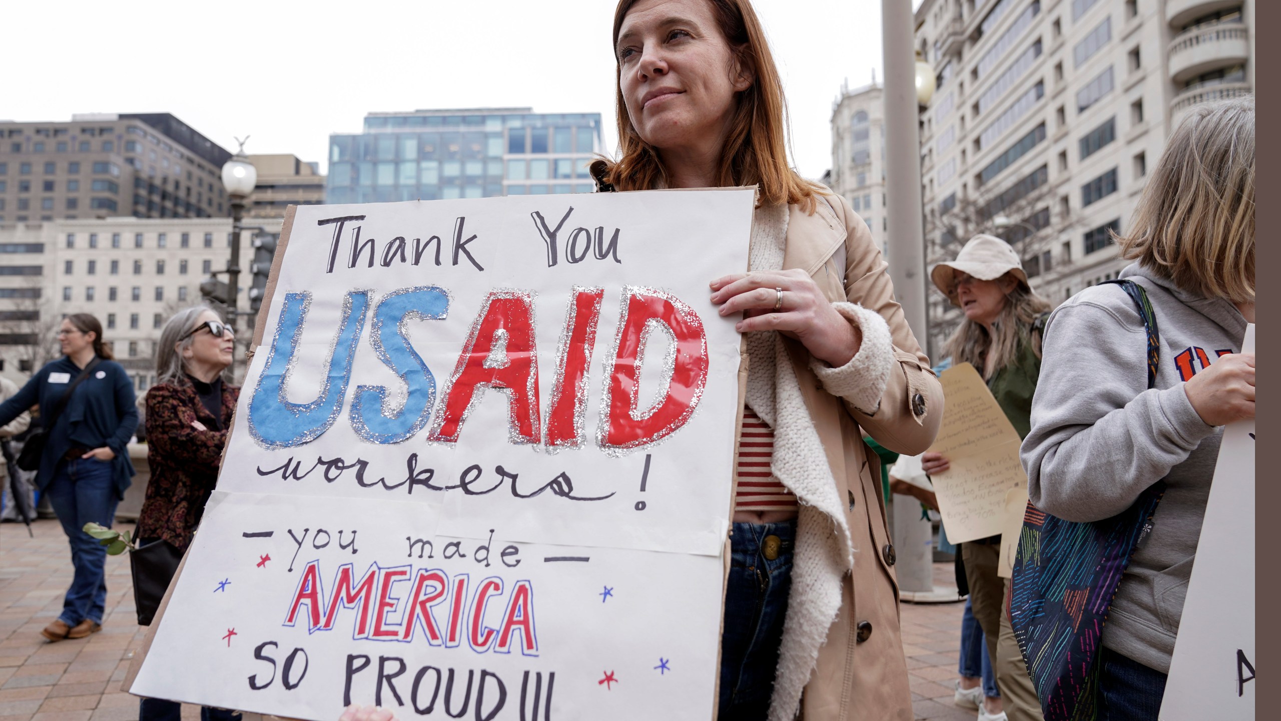 FILE - A person carries a sign in support of the United States Agency for International Development (USAID) workers, as they carry their personal belongings after retrieving them from the USAID's headquarters in Washington, Feb. 27, 2025. (AP Photo/Jose Luis Magana, File)