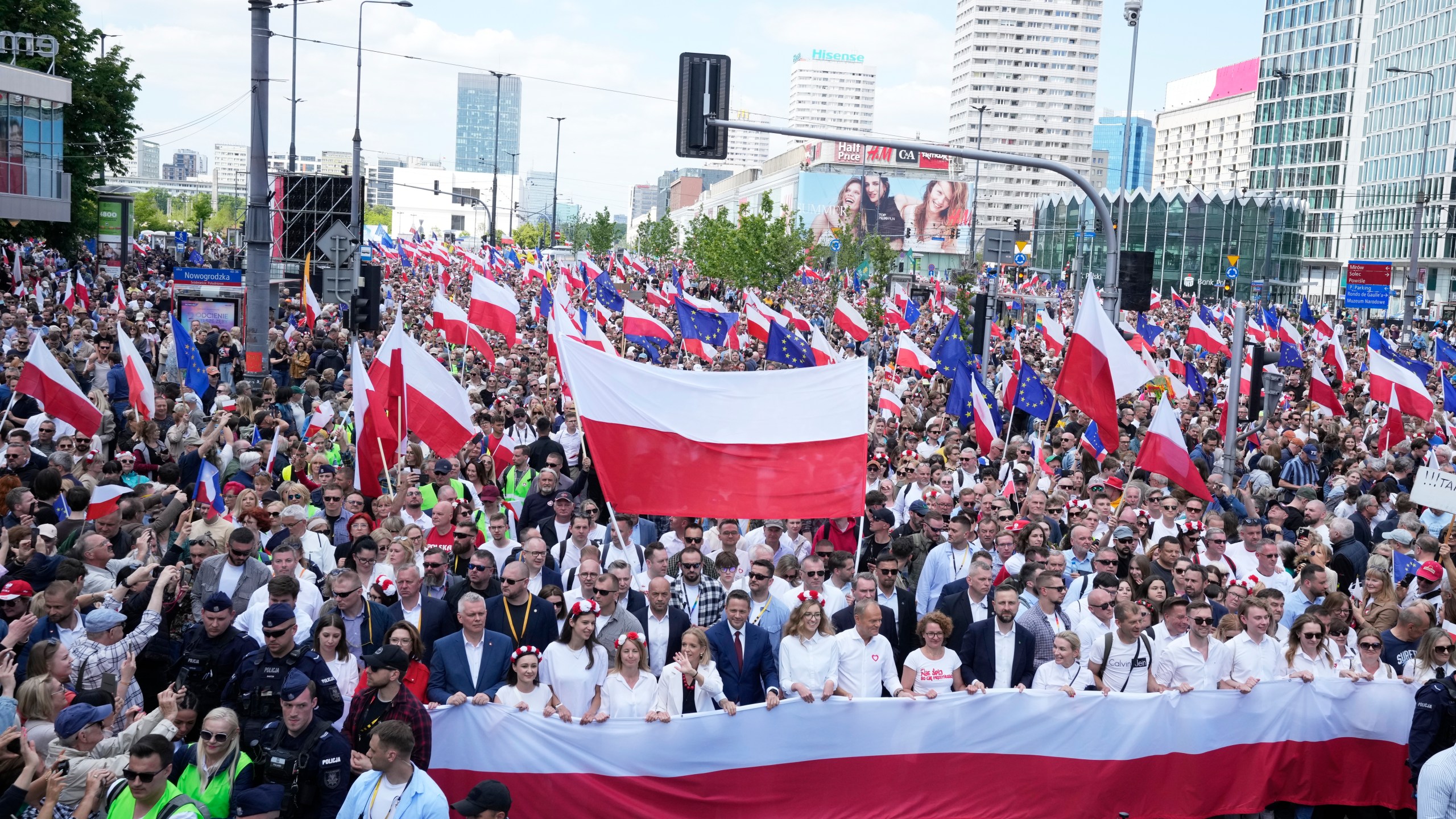 The liberal presidential candidate Rafal Trzaskowski holds a giant polish flag in the first row as he stands next to a waving women during a march one week ahead of a decisive presidential election in Warsaw, Poland on Sunday, May 25, 2025. (AP Photo/Czarek Sokolowski)