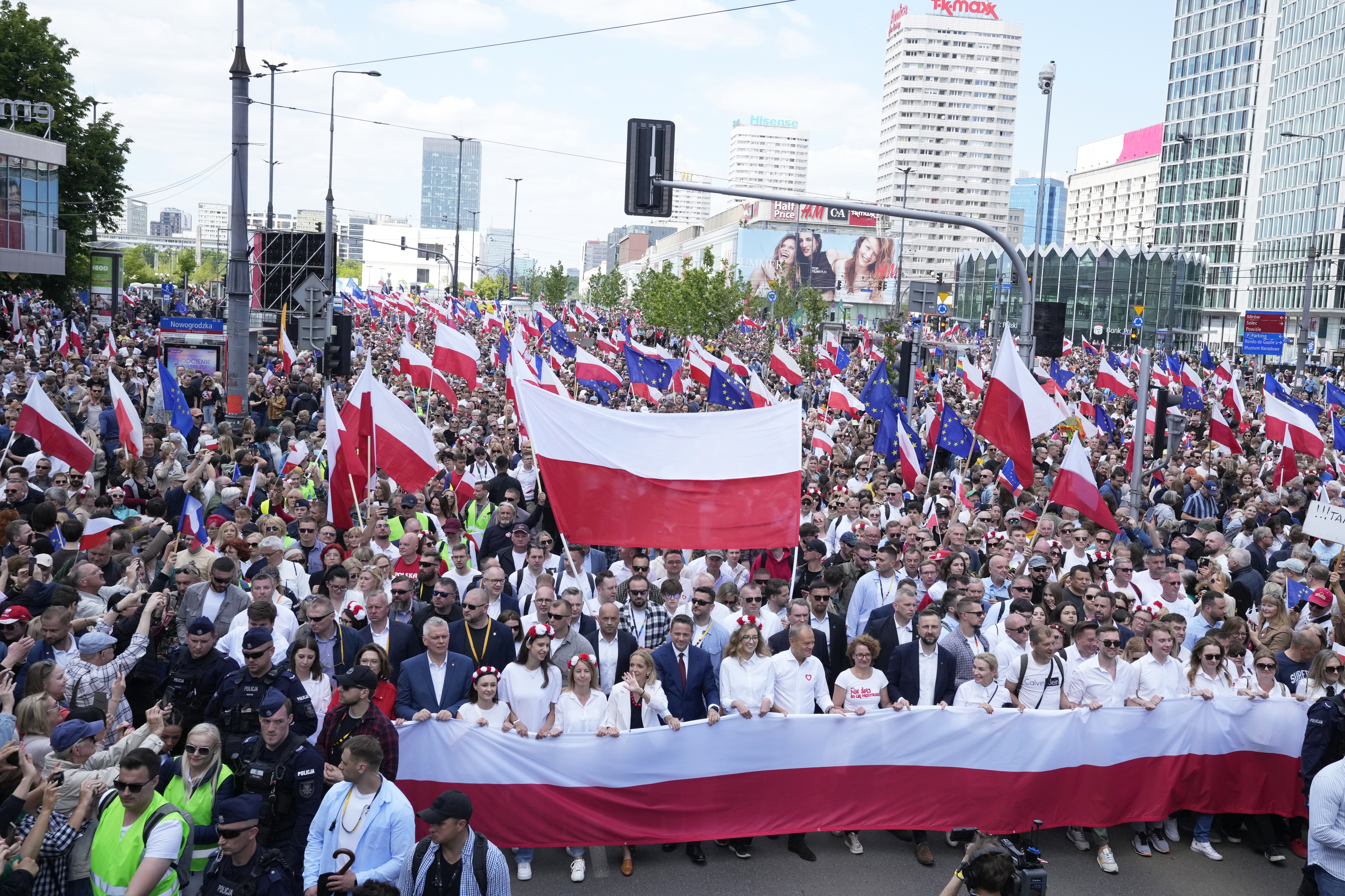 The liberal presidential candidate Rafal Trzaskowski holds a giant polish flag in the first row as he stands next to a waving women during a march one week ahead of a decisive presidential election in Warsaw, Poland on Sunday, May 25, 2025. (AP Photo/Czarek Sokolowski)