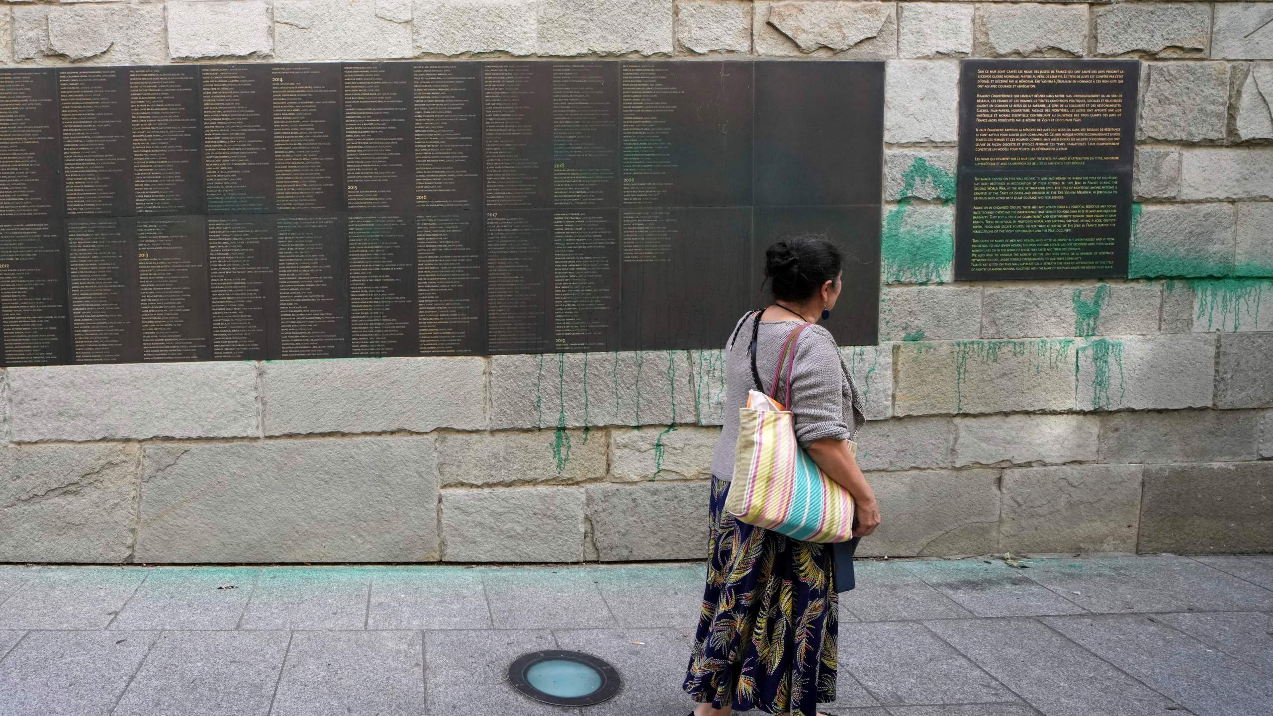 A woman looks at Paris' Shoah Memorial defaced with green paint after several Jewish sites across the capital were defaced with green paint. Saturday, May 31, 2025 in Paris. (AP Photo/Aurelien Morissard)