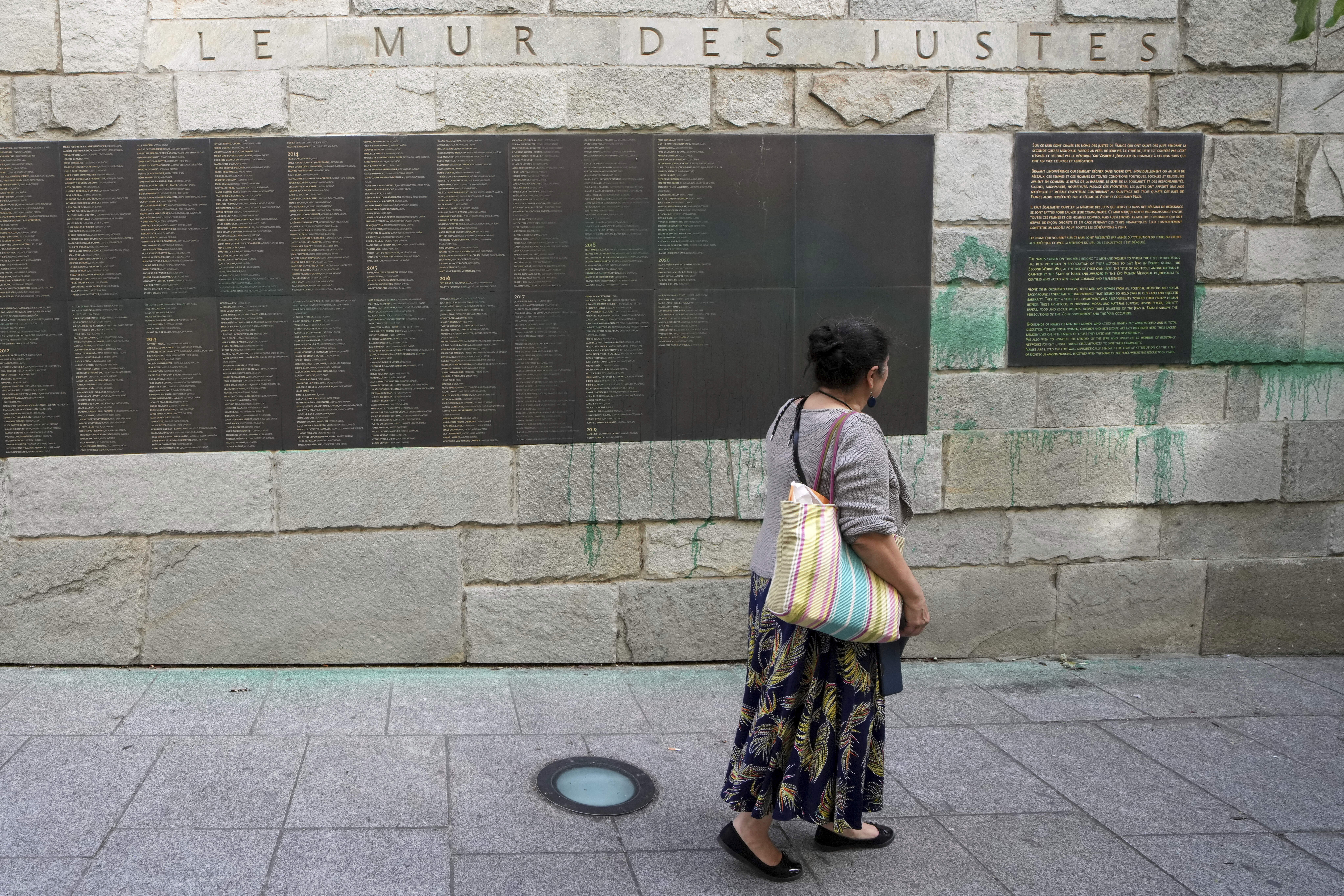 A woman looks at Paris' Shoah Memorial defaced with green paint after several Jewish sites across the capital were defaced with green paint. Saturday, May 31, 2025 in Paris. (AP Photo/Aurelien Morissard)