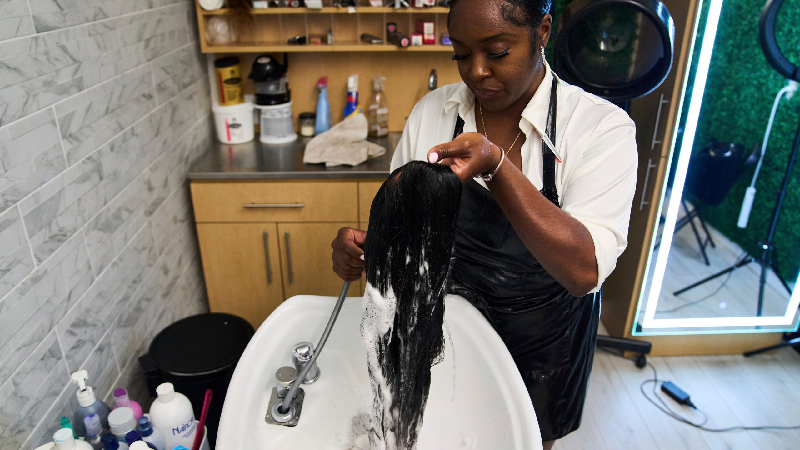 Dajiah Blackshear, a natural hair stylist who specializes in extensions, washes a client's wig during an installation service, Monday, May 5, 2025, at her salon suite in Atlanta. (AP Photo/Stephanie Scarbrough)