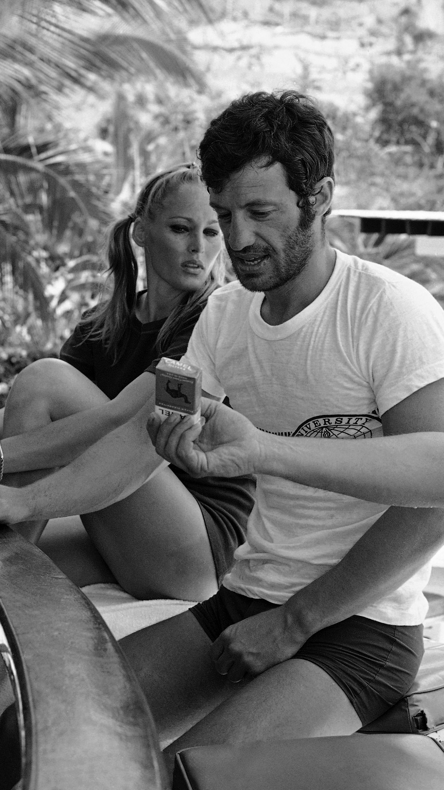 FILE - Accompanied by Swedish Movie star Ursula Andress, French actor Jean Belmondo looks down at a pack of cigarettes being offered to him at their hotel's pool-side bar, April 18, 1967, in Acapulco, Mexico. (AP Photo, File)