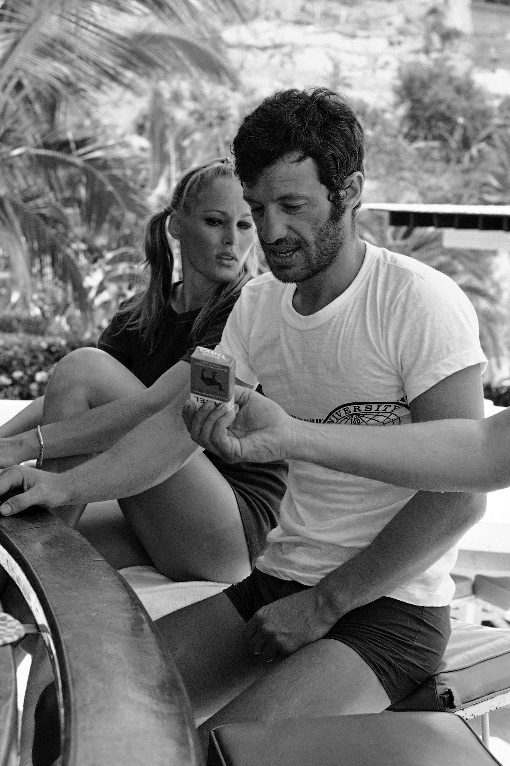 FILE - Accompanied by Swedish Movie star Ursula Andress, French actor Jean Belmondo looks down at a pack of cigarettes being offered to him at their hotel's pool-side bar, April 18, 1967, in Acapulco, Mexico. (AP Photo, File)