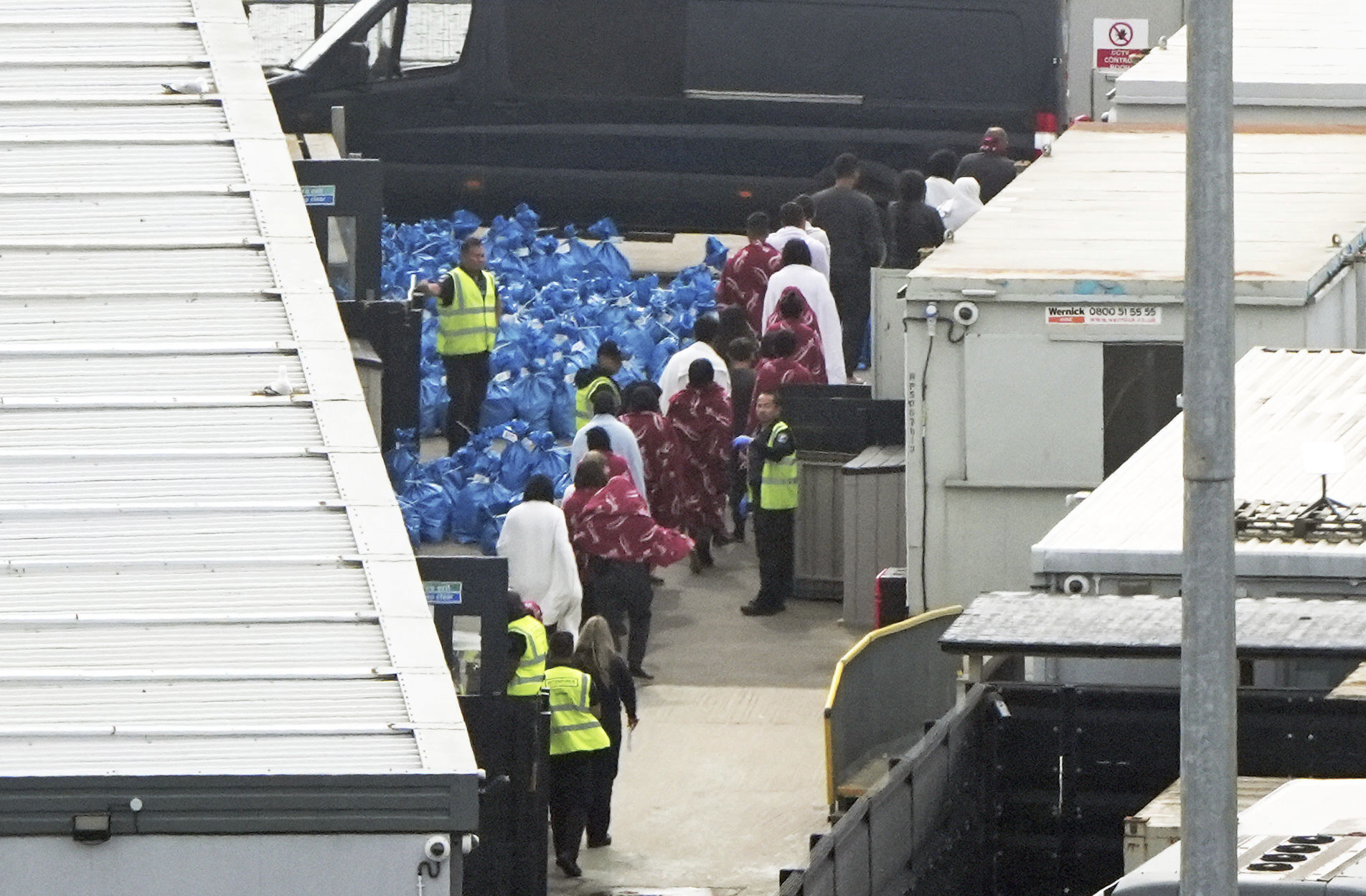 A group of people believed to be migrants are led through the Border Force compound in Dover, England, Sunday June 1, 2025, following a number of small boat crossings in the Channel yesterday. (Gareth Fuller/PA via AP)
