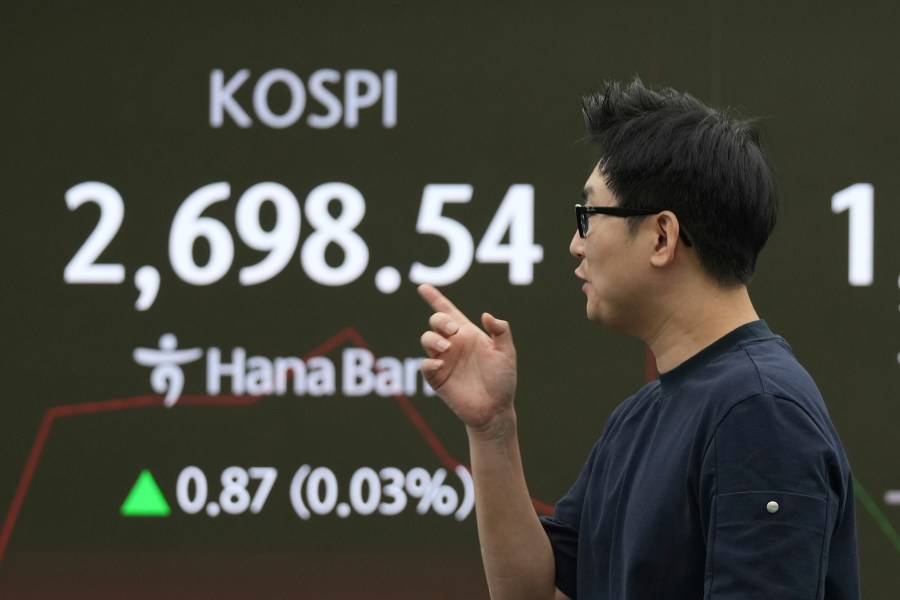 A dealer walks past a screen showing the Korea Composite Stock Price Index (KOSPI) at a dealing room of Hana Bank in Seoul, South Korea, Monday, June 2, 2025. (AP Photo/Lee Jin-man)