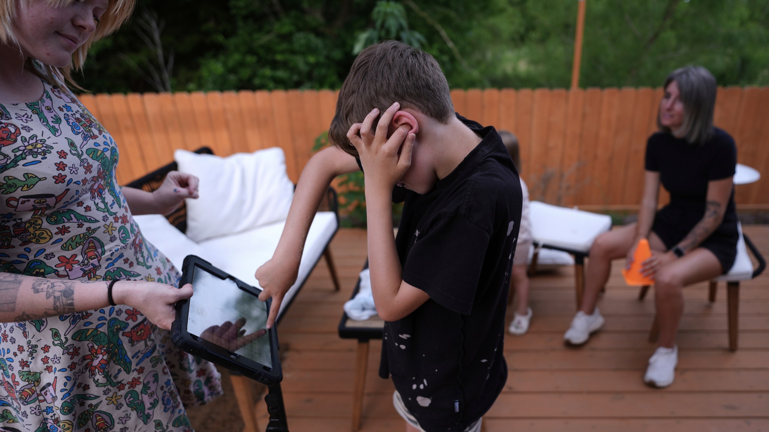 Charlie Lamb, who is diagnosed with autism and is non-verbal, uses an AAC device to communicate with a caregiver, Monday, May 12, 2025, in Austin, Texas. (AP Photo/Eric Gay)