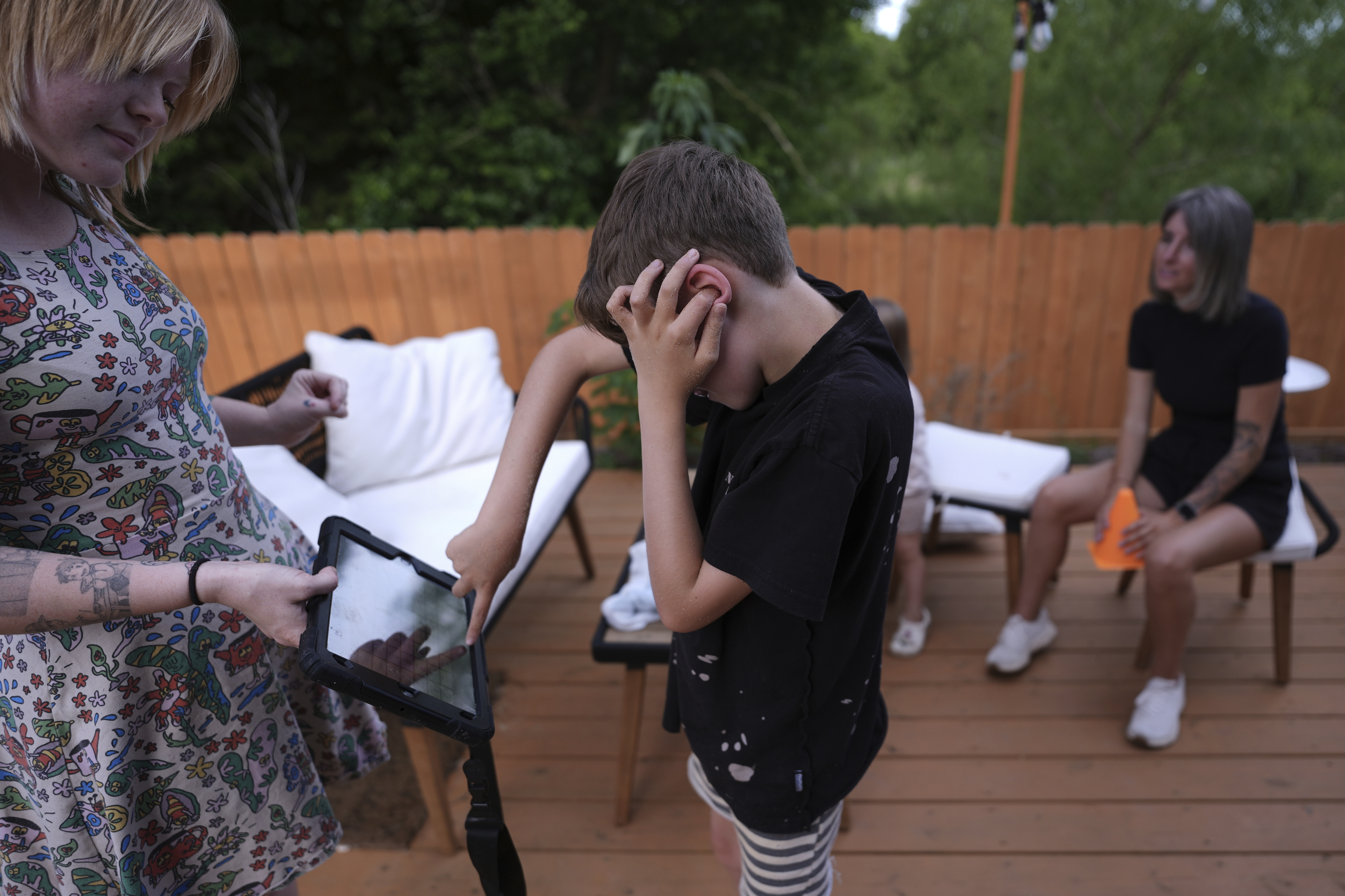 Charlie Lamb, who is diagnosed with autism and is non-verbal, uses an AAC device to communicate with a caregiver, Monday, May 12, 2025, in Austin, Texas. (AP Photo/Eric Gay)