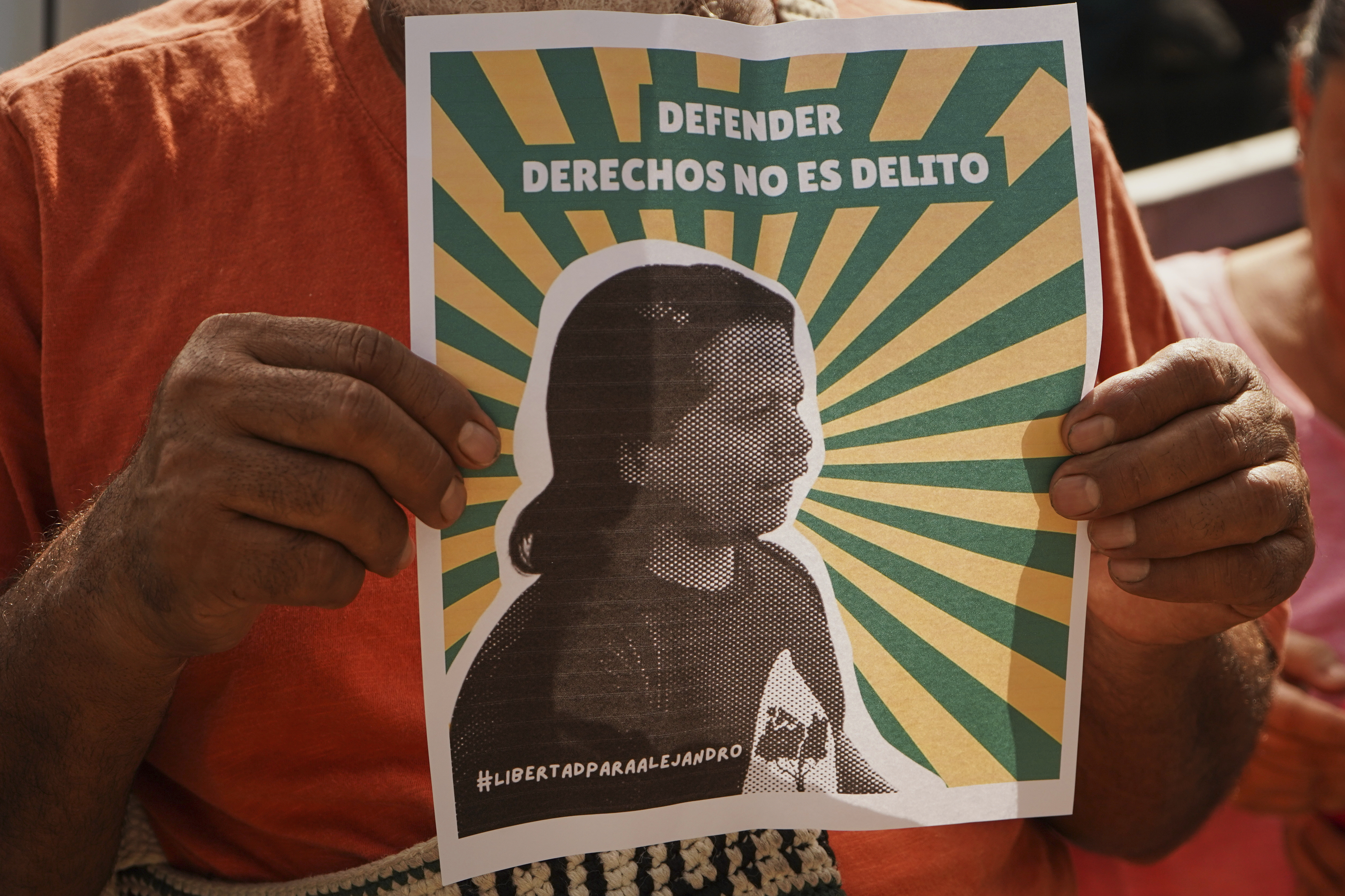 A man holds a poster of Alejandro Henriquez outside the courts during their hearing in Santa Tecla, El Salvador, Friday, May 30, 2025. The National Civil Police arrested them for protesting near the presidnetial residence. (AP Photo/Salvador Melendez)