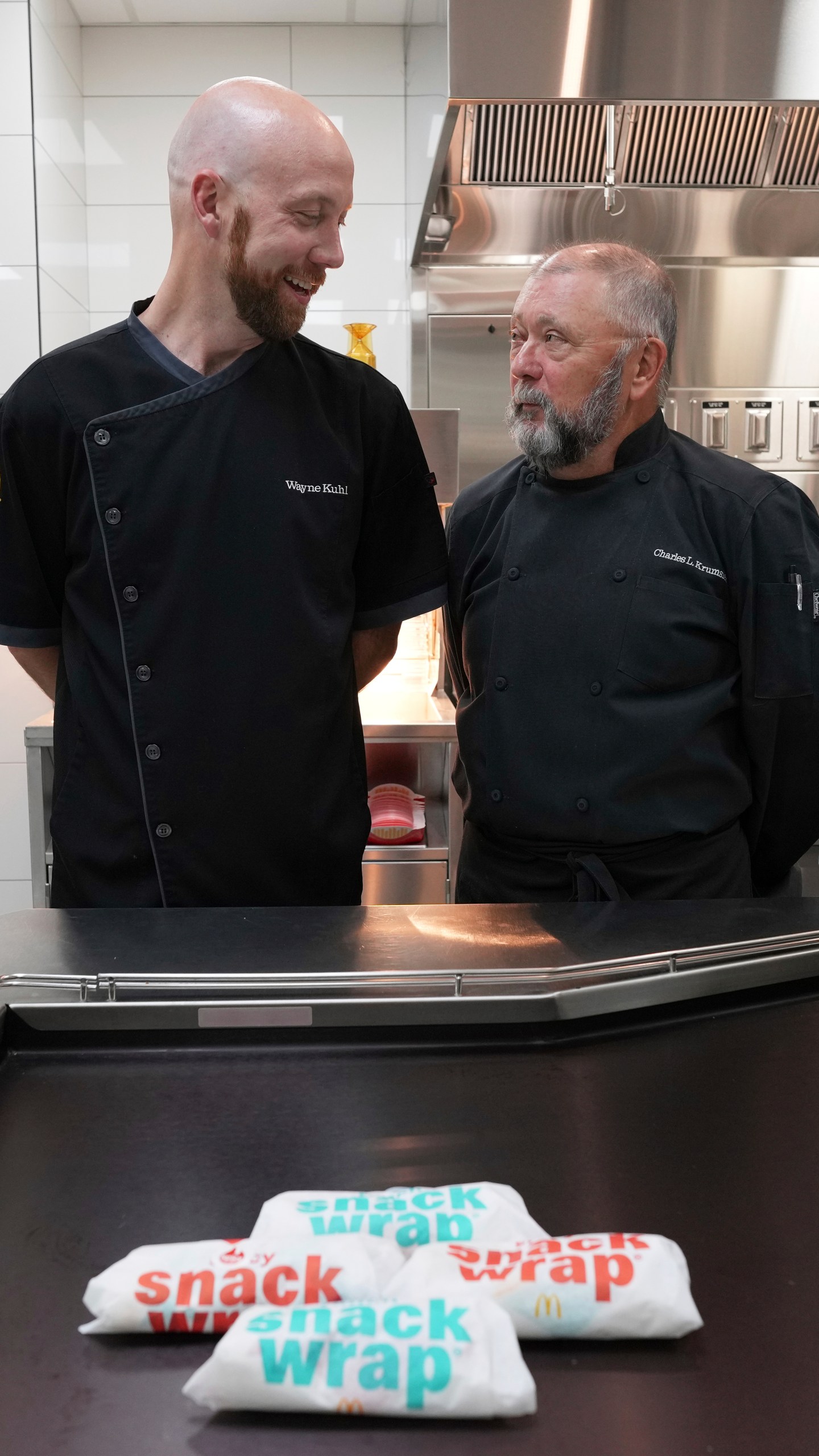 Wayne Kuhl, left, and Charles L. Krumsieka, McDonald's chefs look at each other after made snack wraps at McDonald's Headquarter in Chicago, Thursday, May 29, 2025. (AP Photo/Nam Y. Huh)