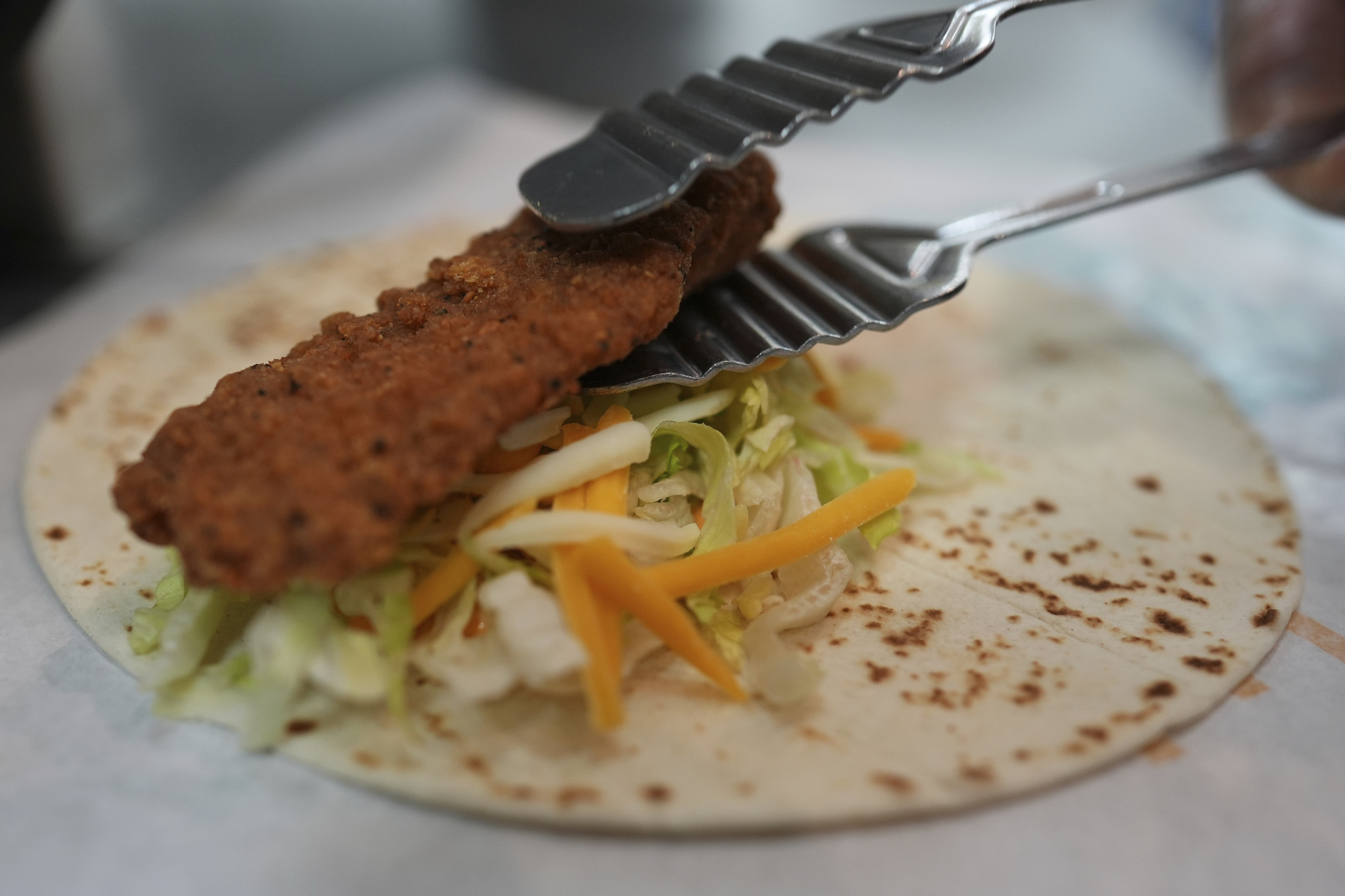 Charles L. Krumsiek, a McDonald's chef, puts a chicken on a tortilla to make a snack wrap at McDonald's Headquarter in Chicago, Thursday, May 29, 2025. (AP Photo/Nam Y. Huh)