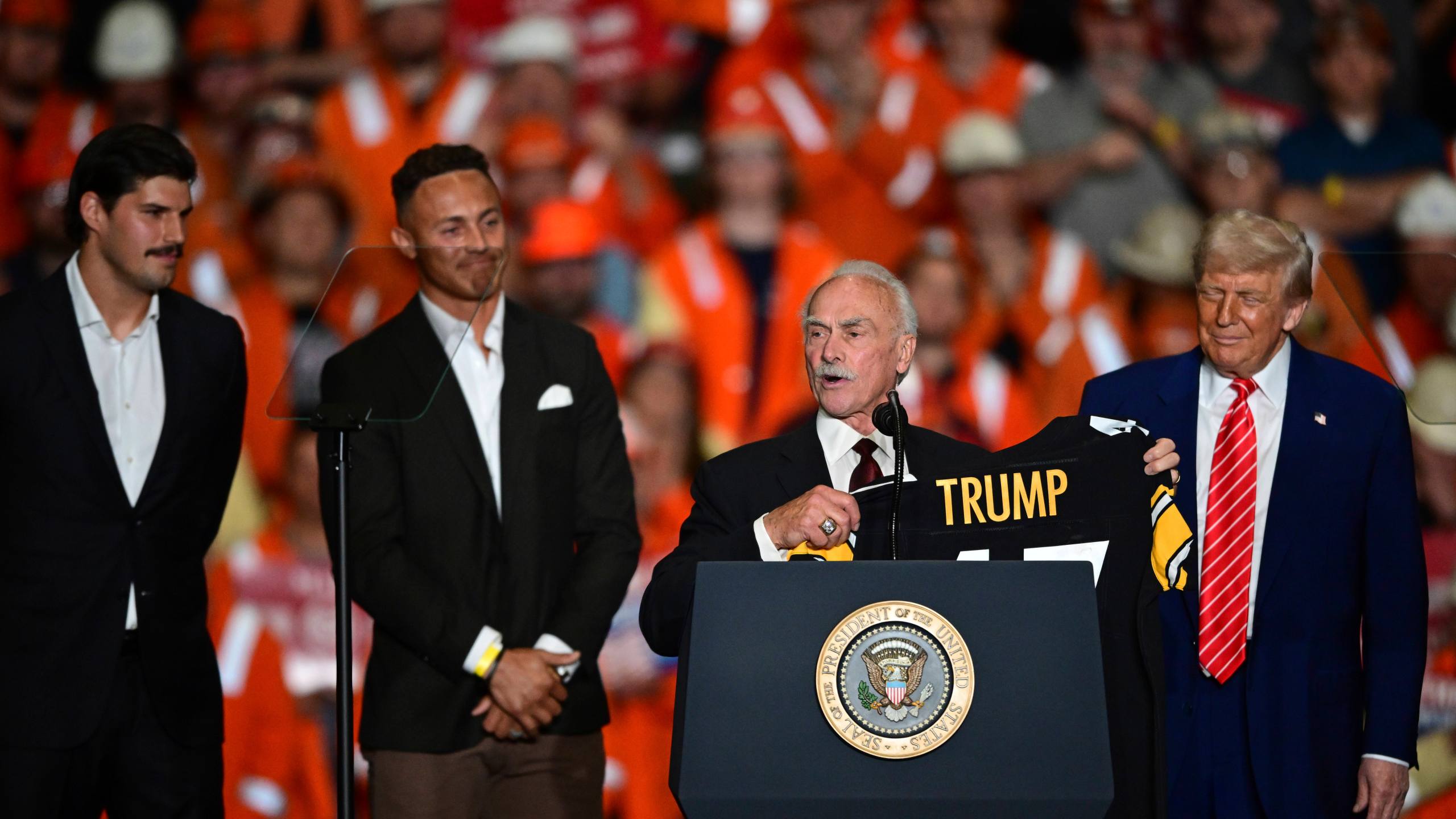Pittsburgh Steelers quarterback Mason Rudolph, Pittsburgh Steelers Miles Killebrew, former Pittsburgh Steelers Rocky Bleier, join President Donald Trump on stage as they present him a Pittsburgh Steelers jersey at the U.S. Steel Mon Valley Works-Irvin plant, Friday, May 30, 2025, in West Mifflin, Pa. (AP Photo/David Dermer)