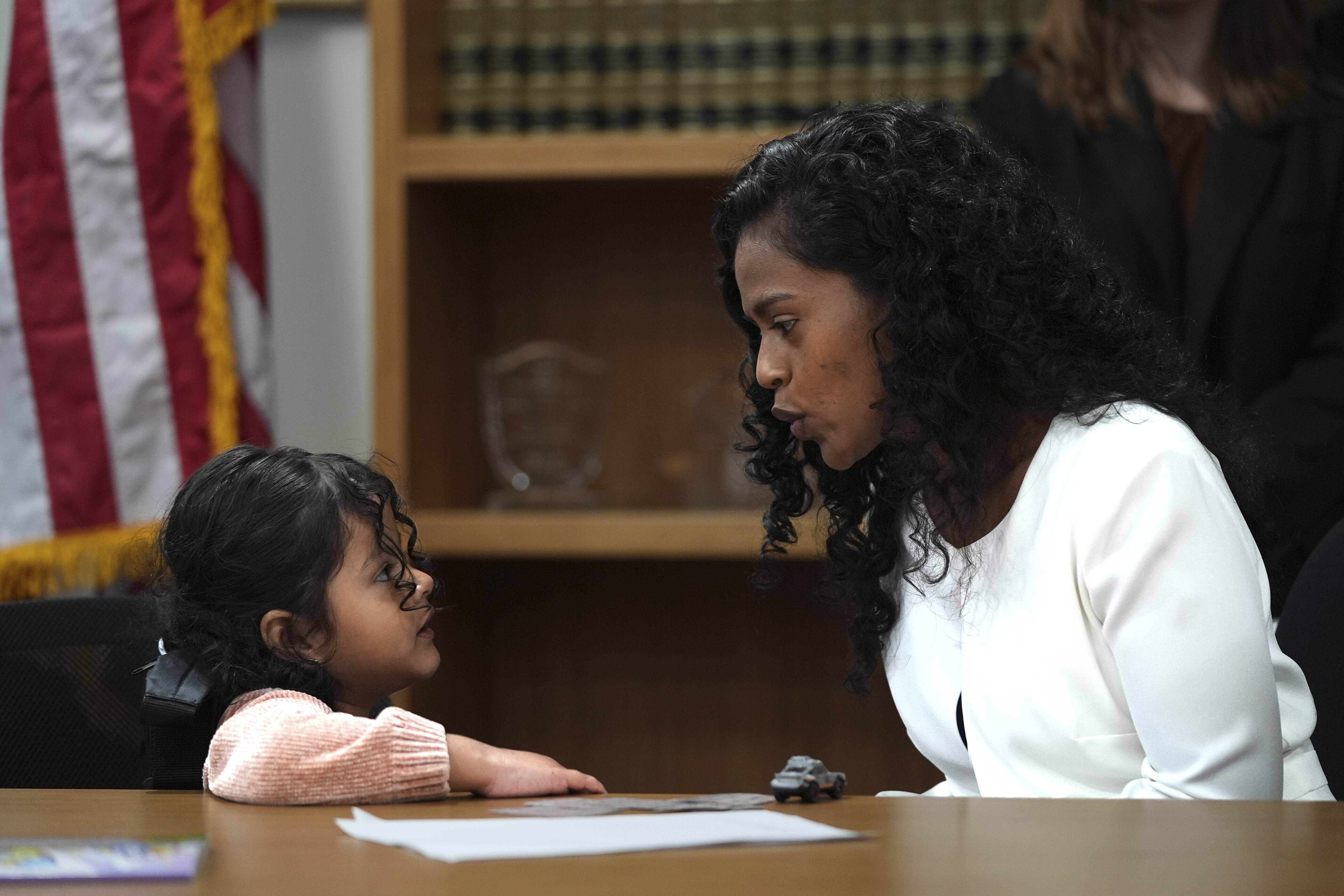 Deysi Vargas, left, talks to her 4-year-old daughter, who has short bowel syndrome, at a news conference in Los Angeles, Wednesday, May 28, 2025, after their humanitarian parole was terminated and they were ordered to self-deport. (AP Photo/Jae C. Hong)